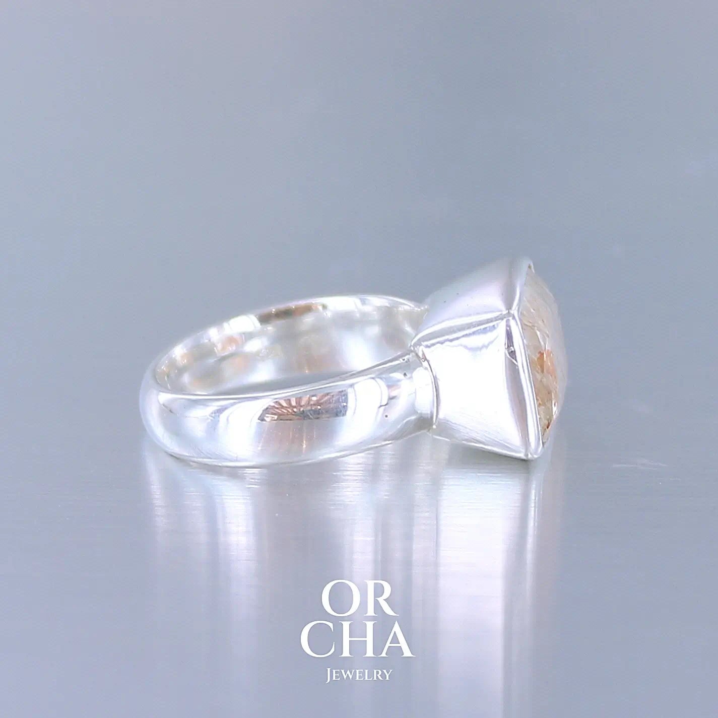 Profil d'une bague cocktail pour femme en argent massif sertie d'une pierre de soleil oranges de très belle qualité, pierre transparente avec inclusions scintillantes d'hématites.Pierre naturelle facettée de forme rectangulaire. Tailles 54. Bijoux unique, éthique et durable présenté dans un coffret de notre marque, prêt à offrir. Livraison offerte, certificat d'authenticité, service client.