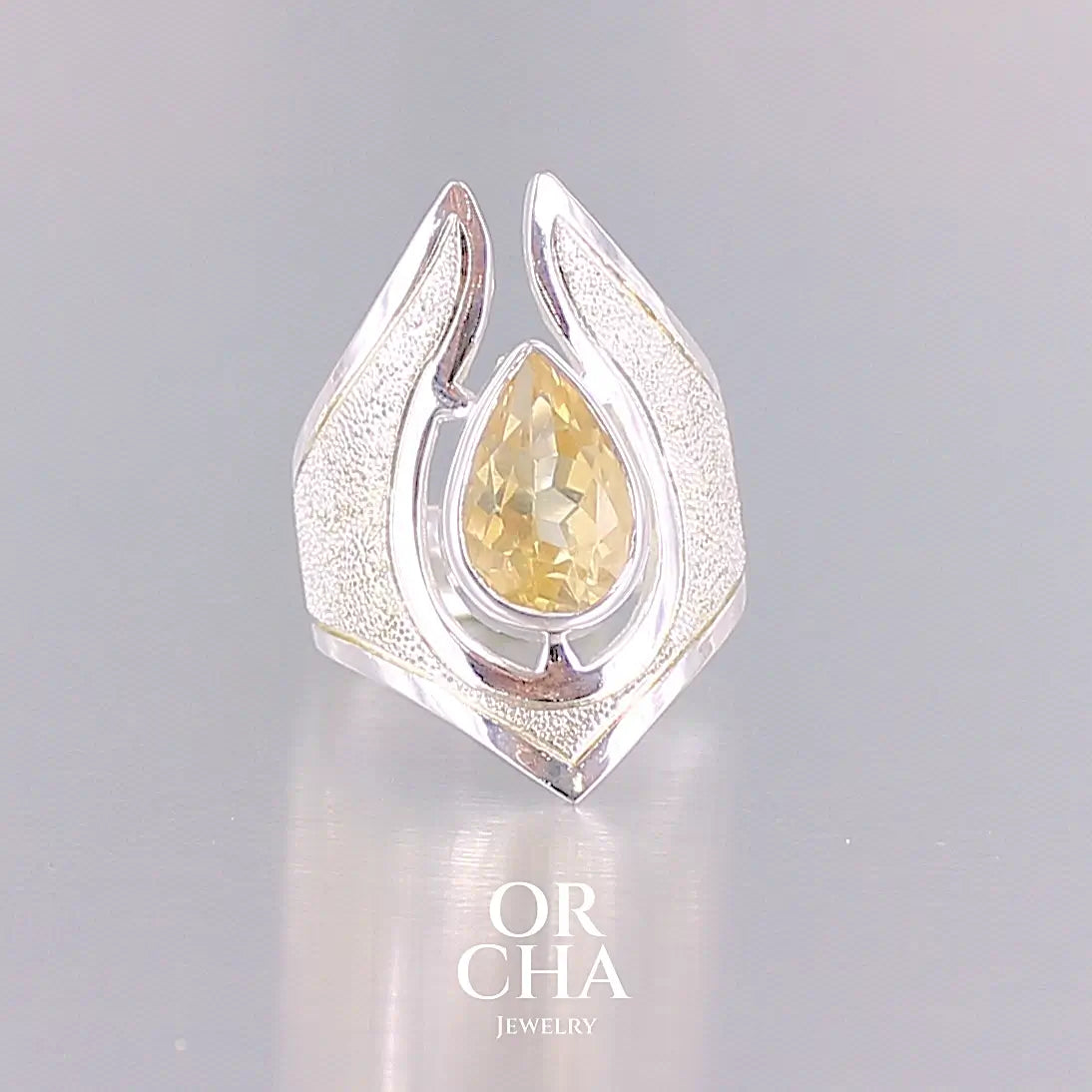 Grande bague contemporaine pour femme en argent massif sertie d'une Citrine. Pierre facettée en forme de goutte de qualité transparente, propre à l'oeil. Pierre naturelle de couleur jaune or lumineux. Bijoux unique, éthique et durable présenté dans un coffret de notre marque, prêt à offrir. Livraison offerte, certificat d'authenticité, service client.