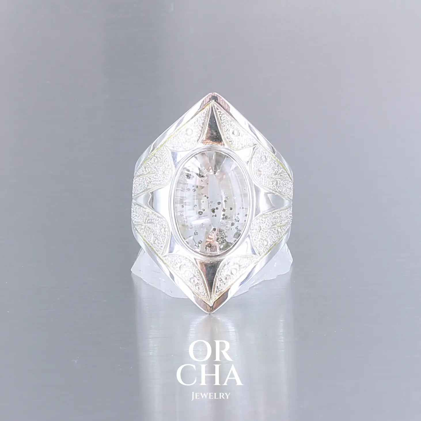 Bague pour femme en argent massif sculptées d'étoiles et autres corps célestes sertie d'un quartz à inclusions. Pierre cabochon de forme ovale, incolore avec inclusions dorés de pyrite de fer . Qualité  transparente, pierre naturelle. Taille 59. Bijoux unique, éthique et durable présenté dans un coffret de notre marque, prêt à offrir. Livraison offerte, certificat d'authenticité, service client.