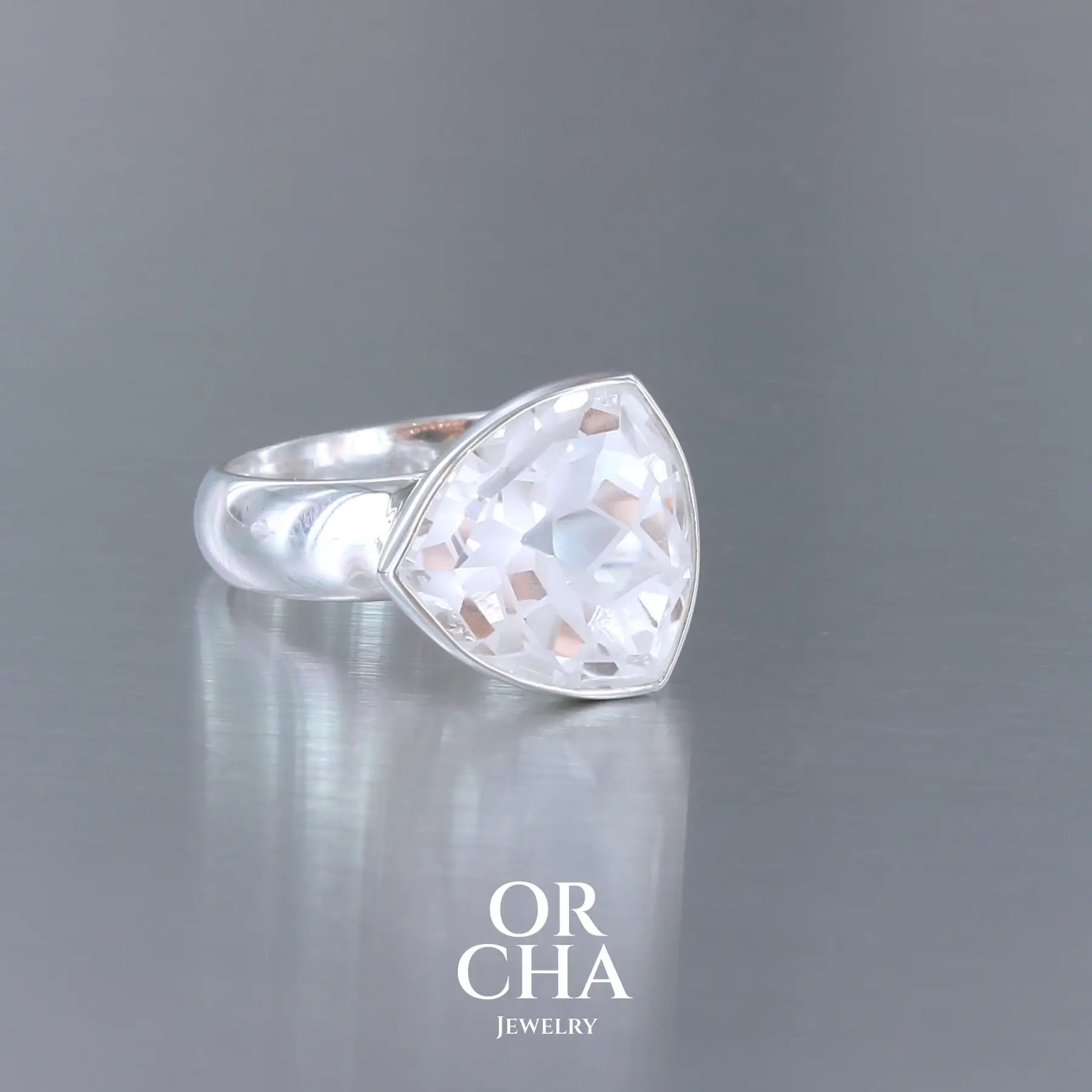 Bague cocktail pour femme en argent massif sertie d'un Cristal de roche gravé d'une fleur de vie. Pierre facettée de forme carrée de qualité transparente, propre à l'oeil. Pierre naturelle incolore et blanche sur les parties gravées. Bague disponible en différentes tailles. Bijoux unique, éthique et durable présenté dans un coffret de notre marque, prêt à offrir. Livraison offerte, certificat d'authenticité, service client.