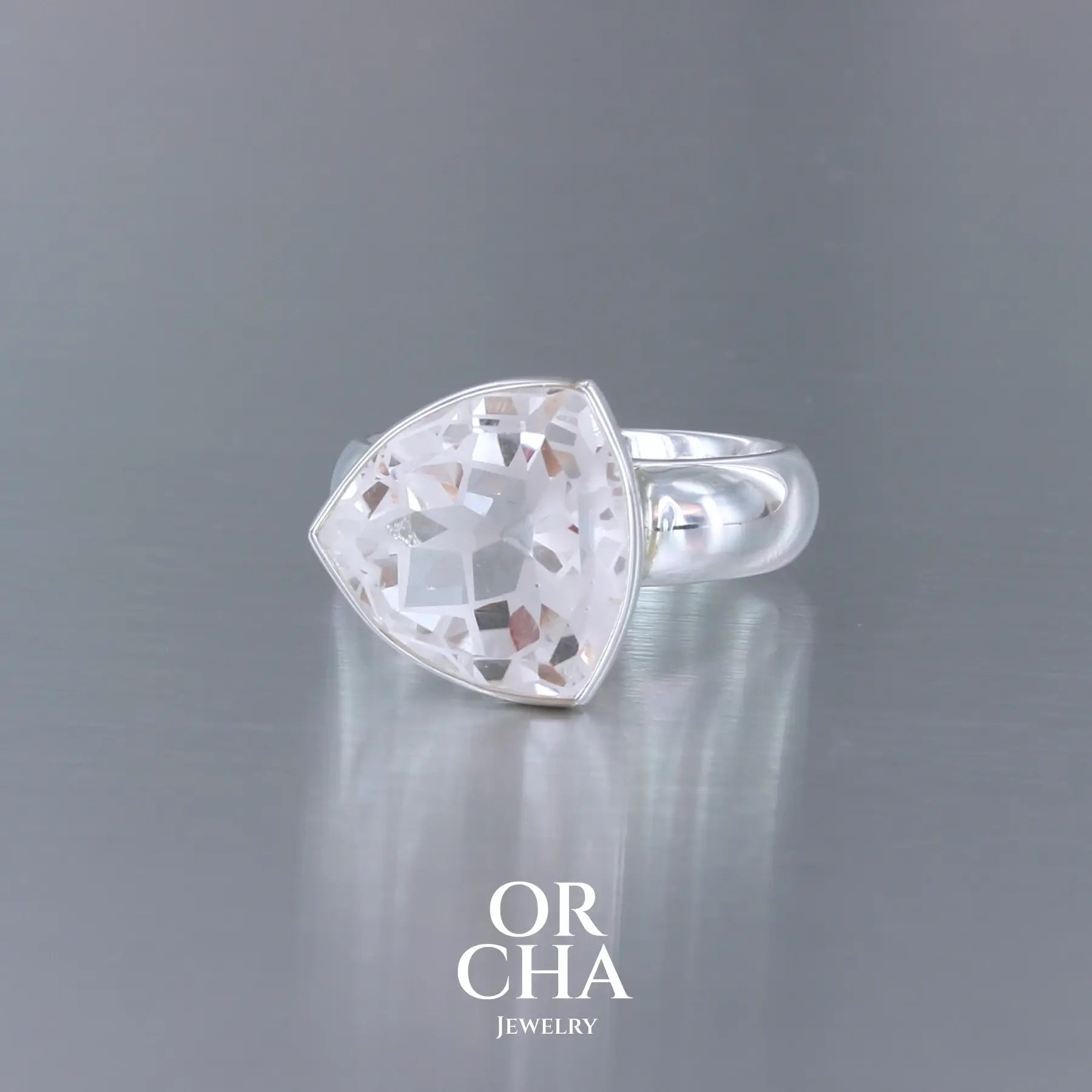Bague cocktail pour femme en argent massif sertie d'un Cristal de roche gravé d'une fleur de vie. Pierre facettée de forme carrée de qualité transparente, propre à l'oeil. Pierre naturelle incolore et blanche sur les parties gravées. Bague disponible en différentes tailles. Bijoux unique, éthique et durable présenté dans un coffret de notre marque, prêt à offrir. Livraison offerte, certificat d'authenticité, service client.