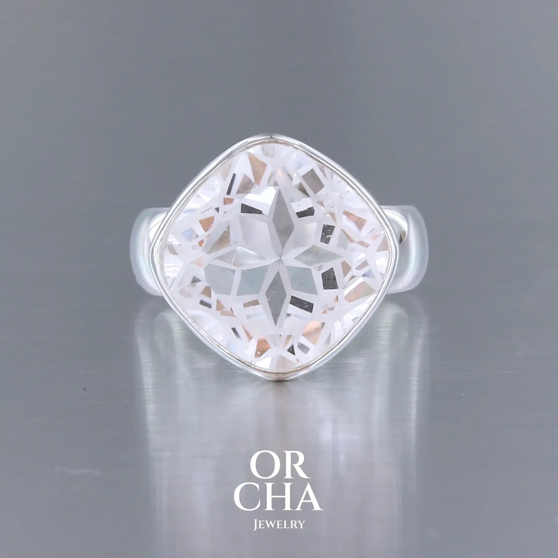 Bague cocktail pour femme en argent massif sertie d'un Cristal de roche gravé d'une fleur de vie. Pierre facettée de forme carrée de qualité transparente, propre à l'oeil. Pierre naturelle incolore et blanche sur les parties gravées. Bague réalisée en taille 60. Bijoux unique, éthique et durable présenté dans un coffret de notre marque, prêt à offrir. Livraison offerte, certificat d'authenticité, service client.