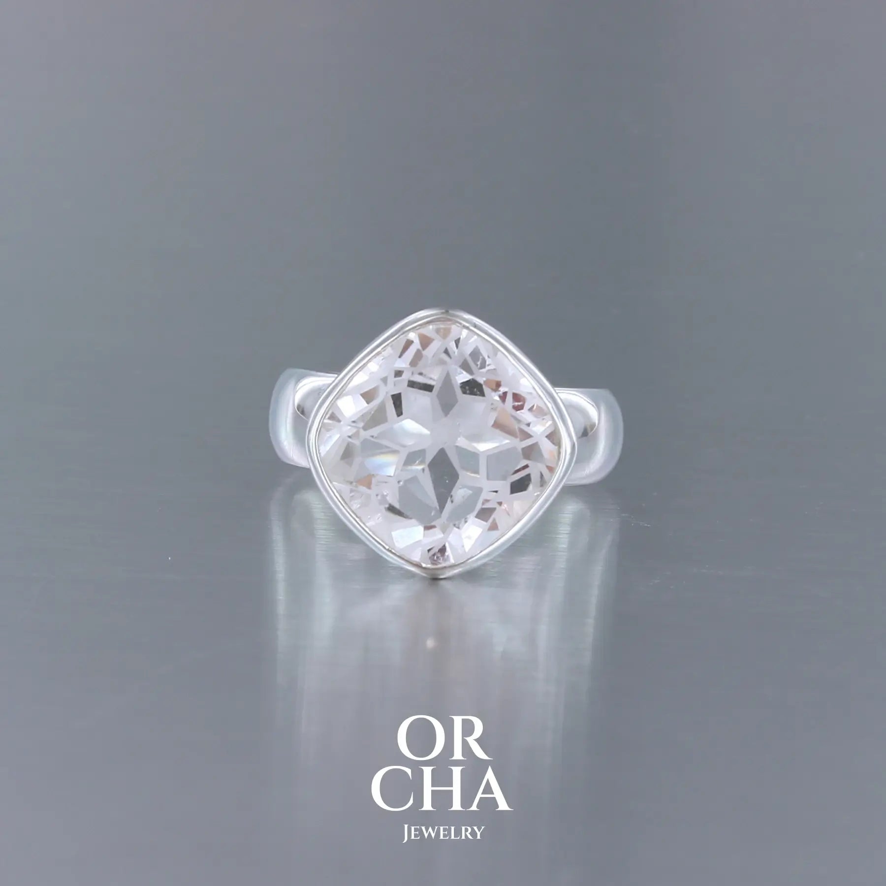 Bague cocktail pour femme en argent massif sertie d'un Cristal de roche gravé d'une fleur de vie. Pierre facettée de forme carrée de qualité transparente, propre à l'oeil. Pierre naturelle incolore et blanche sur les parties gravées. Bague réalisée en taille 52 ou 54. Bijoux unique, éthique et durable présenté dans un coffret de notre marque, prêt à offrir. Livraison offerte, certificat d'authenticité, service client.