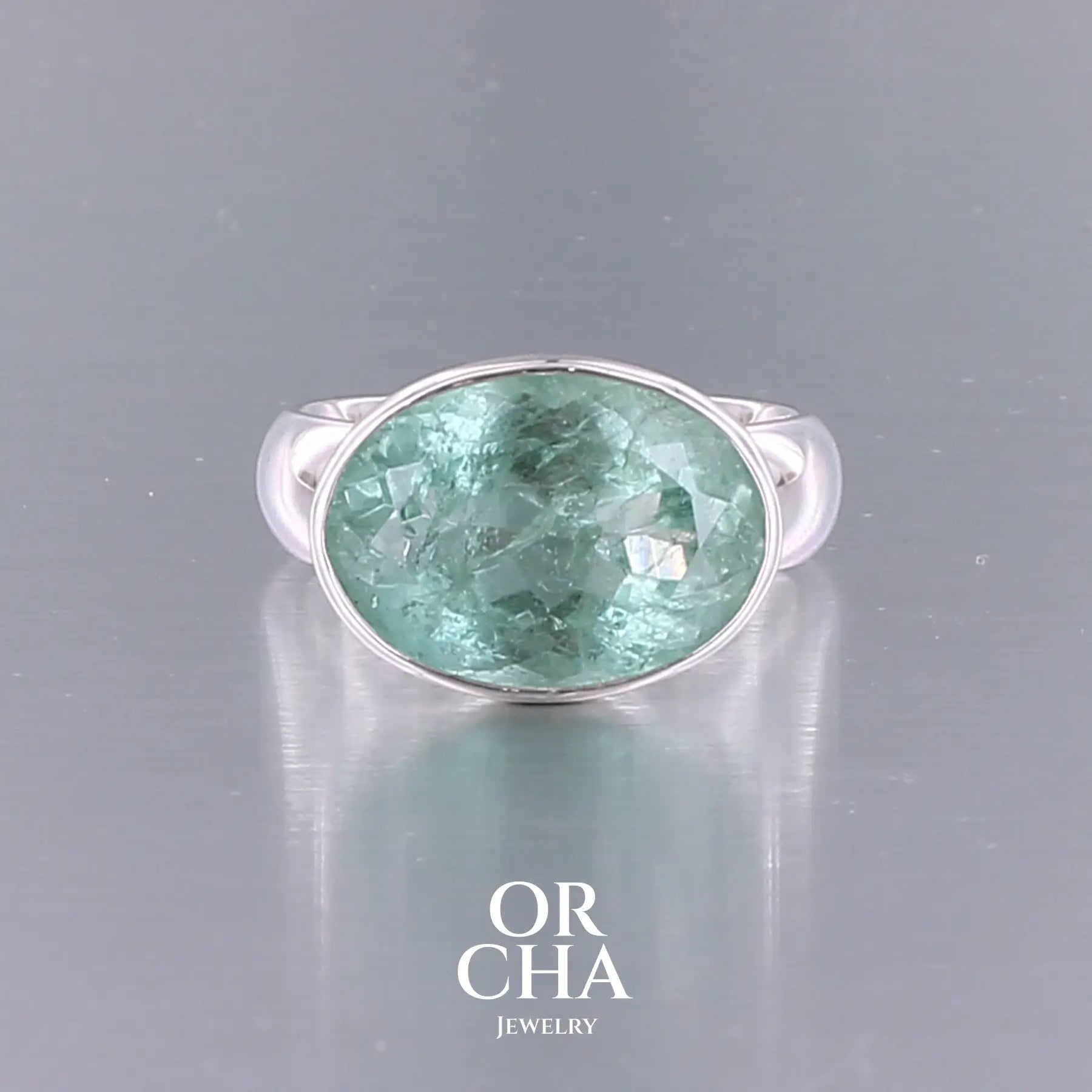Bague cocktail pour femme en argent massif sertie d'une Aigue marine ovale facettée de couleur bleue verte. Pierre de 17 carats de qualité transparente avec inclusions naturelles. Bague réalisée en taille 60. Bijoux unique, éthique et durable présenté dans un coffret de notre marque, prêt à offrir. Livraison offerte, certificat d'authenticité, service client.
