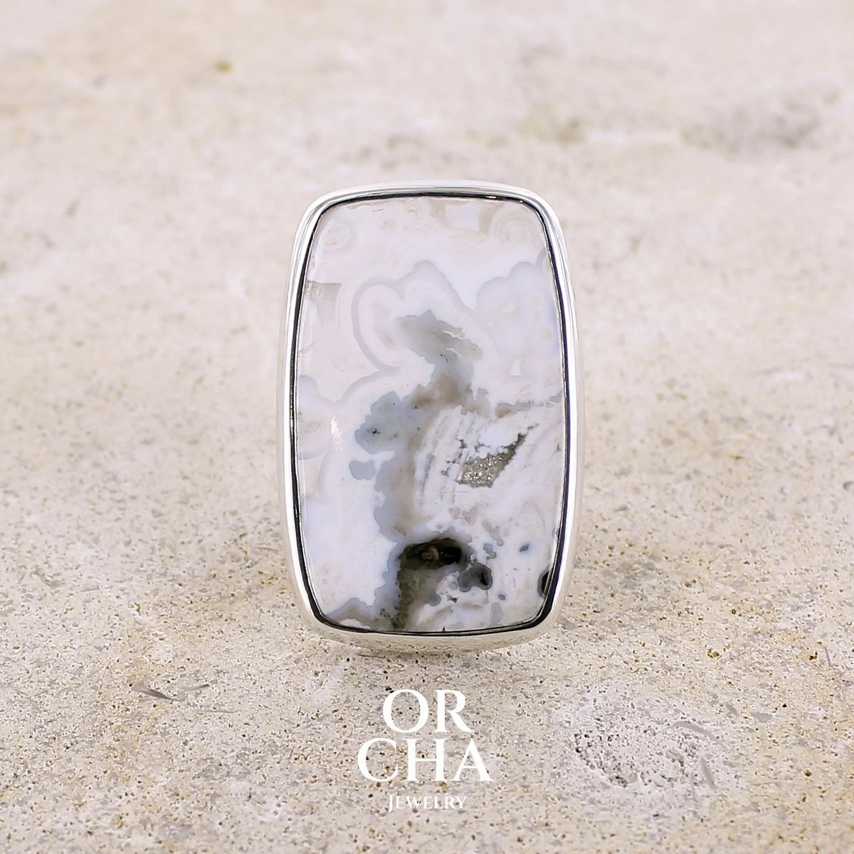 Bague pour femme en argent massif sertie d'un cabochon rectangulaire de jaspe océan de couleur blanc crème, gris, kaki et beige. Pierre de qualité opaque. Bijou unique réalisée en taille 54 par Orchajewelry
