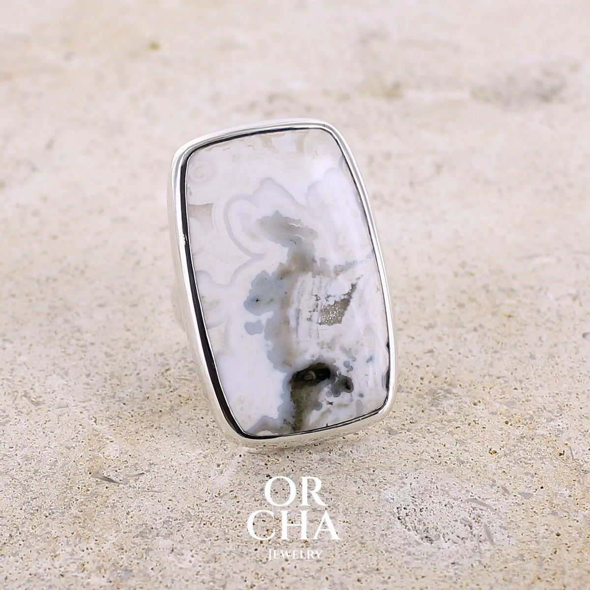 Bague pour femme en argent massif sertie d'un cabochon rectangulaire de jaspe océan de couleur blanc crème, gris, kaki et beige. Pierre de qualité opaque. Bijou unique réalisée en taille 54 par Orchajewelry