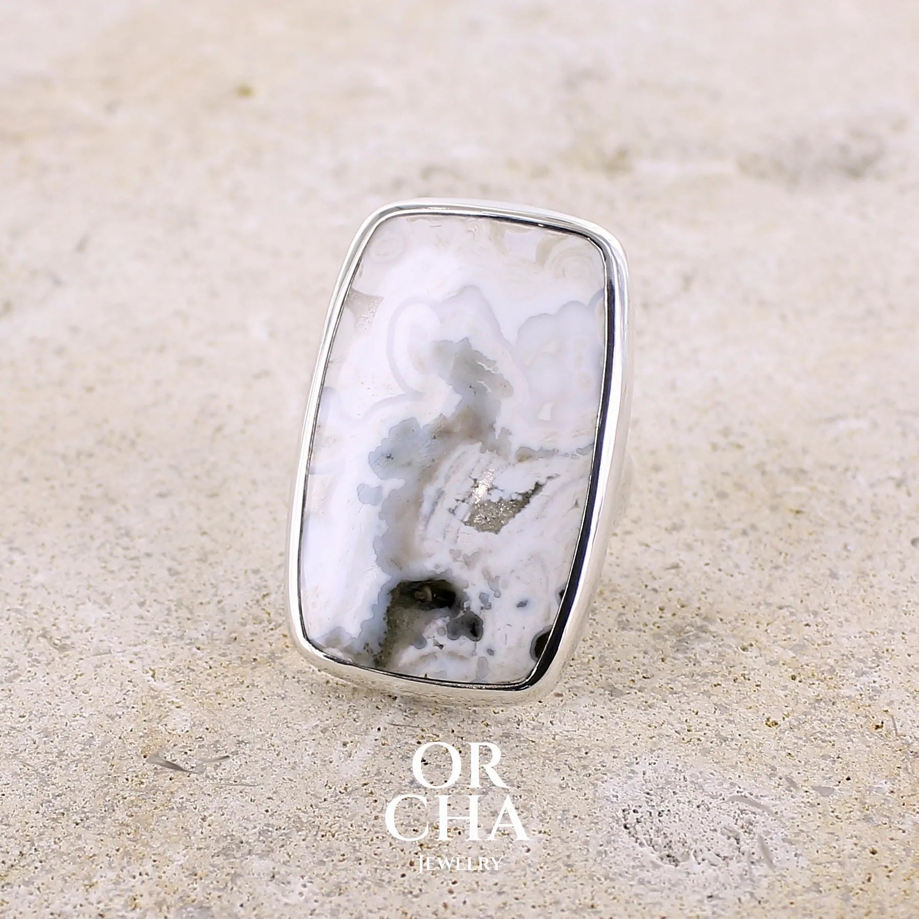 Bague pour femme en argent massif sertie d'un cabochon rectangulaire de jaspe océan de couleur blanc crème, gris, kaki et beige. Pierre de qualité opaque. Bijou unique réalisée en taille 54 par Orchajewelry