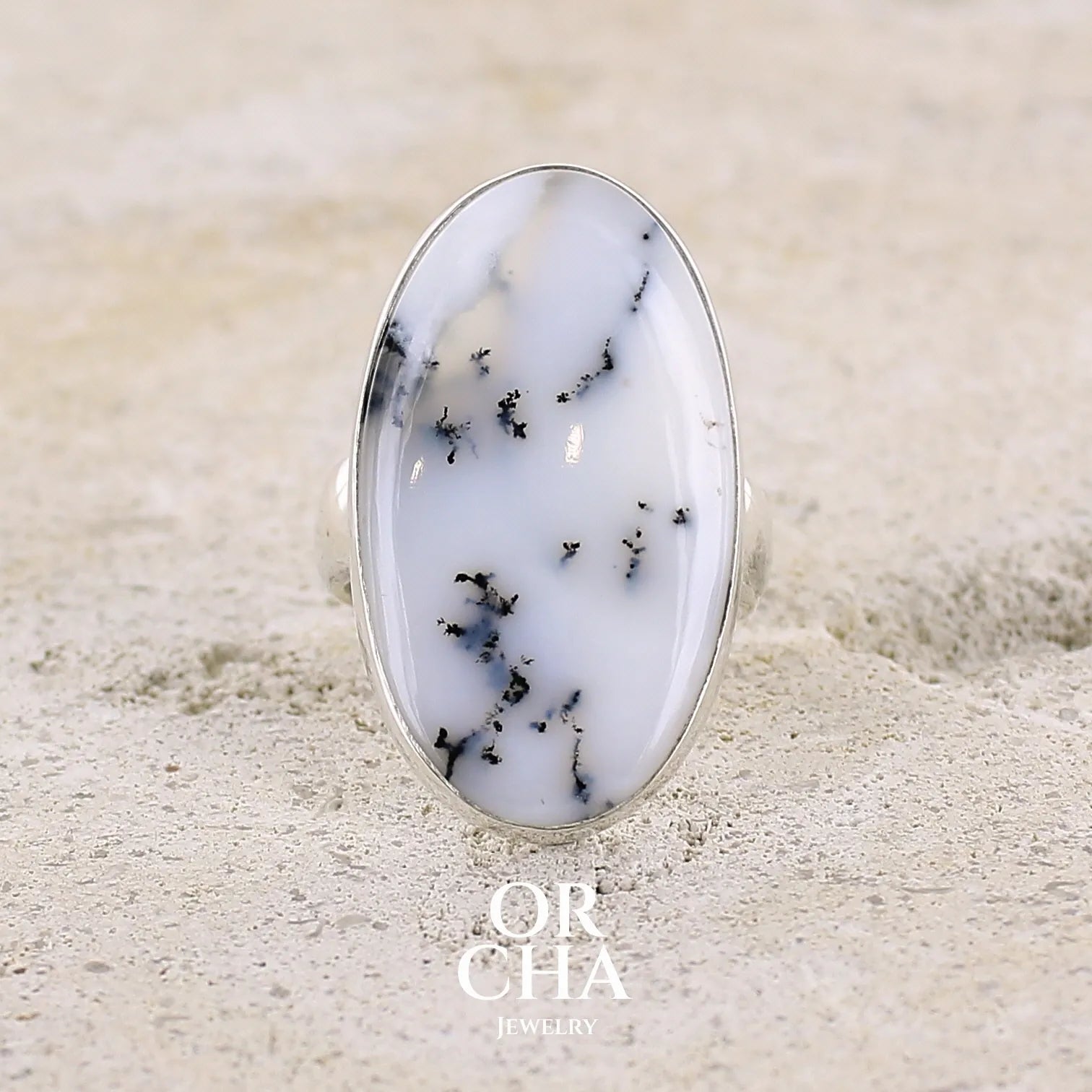 Bague pour femme en argent massif sertie d'un cabochon d'agate dendritique de couleur blanche et noire. Pierre de forme ovale de qualité translucide à inclusions paysages de manganèse contrastées. Bijou unique réalisée en taille 58,5 par Orcha Jewelry