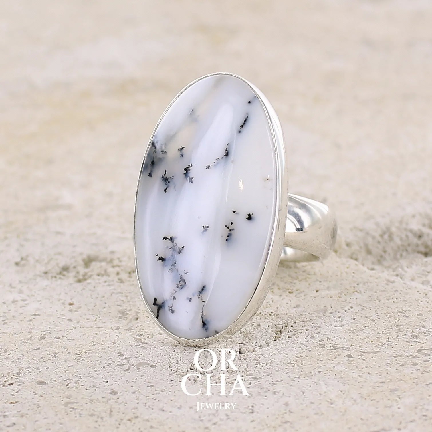 Bague pour femme en argent massif sertie d'un cabochon d'agate dendritique de couleur blanche et noire. Pierre de forme ovale de qualité translucide à inclusions paysages de manganèse contrastées. Bijou unique réalisée en taille 58,5 par Orcha Jewelry