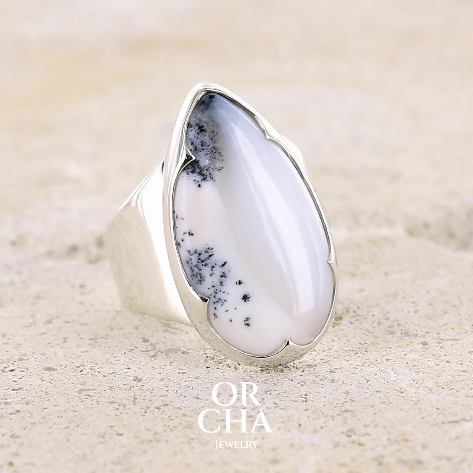 Bague pour femme en argent massif sertie d'un cabochon d'agate dendritique de couleur blanche et noire. Pierre translucide à inclusions paysages de manganèse contrastées. Bijou unique réalisée en taille 58 par Orcha Jewelry