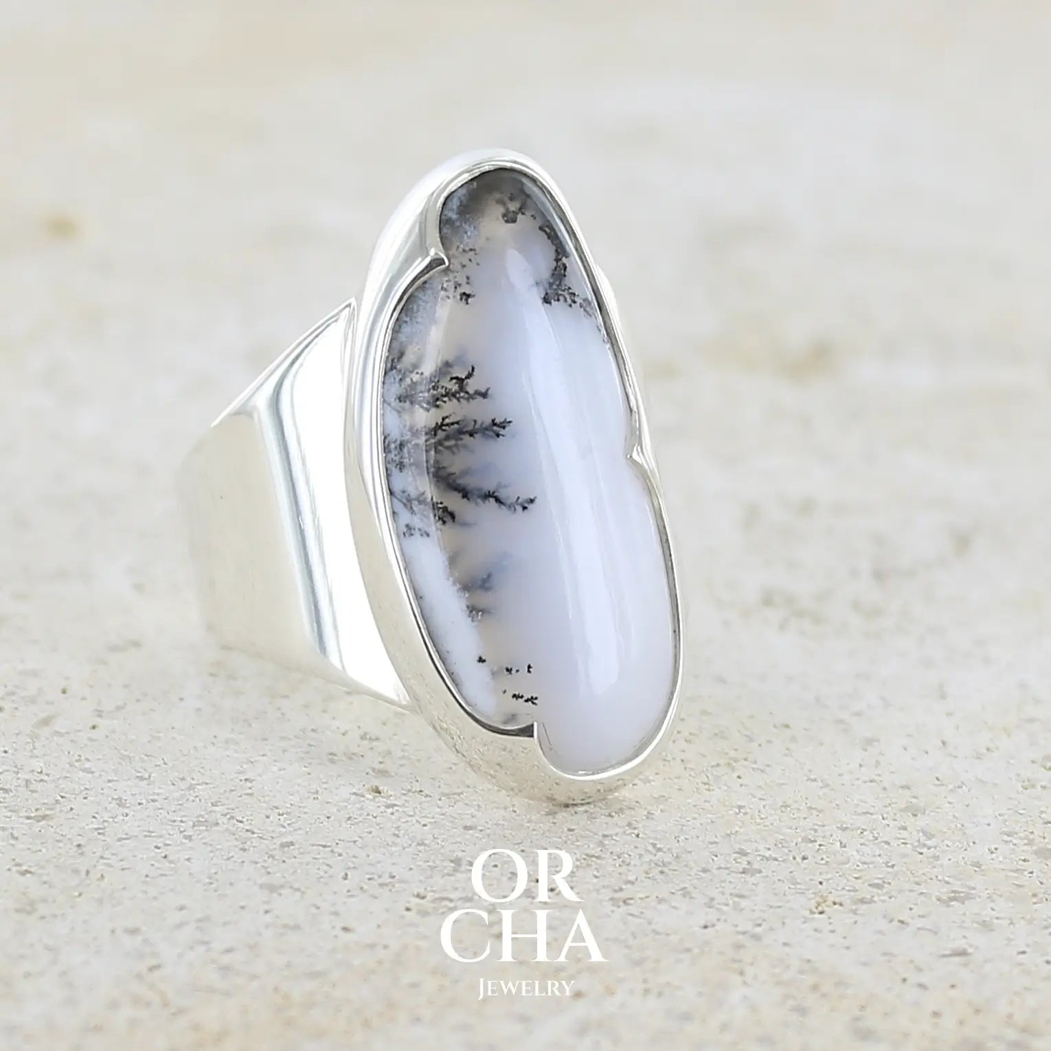 Bague pour femme en argent massif sertie d'un cabochon d'agate dendritique de couleur blanc pur et noir. Pierre opaque translucide à inclusions arborescentes de dendrites de manganèse noires contrastées. Bijou unique réalisée en taille 58 par Orchajewelry