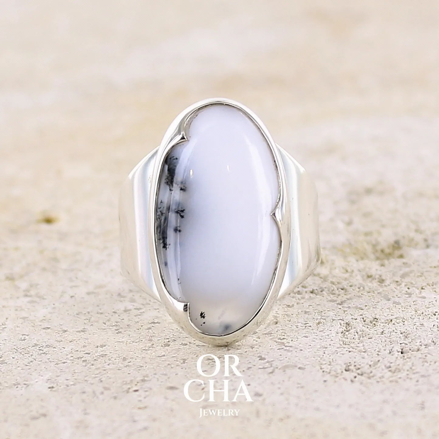 Bague pour femme en argent massif sertie d'un cabochon d'agate dendritique de couleur blanche et noire. Pierre de forme ovale de qualité translucide à inclusions paysages de manganèse contrastées. Bijou unique réalisée en taille 58 par Orcha Jewelry