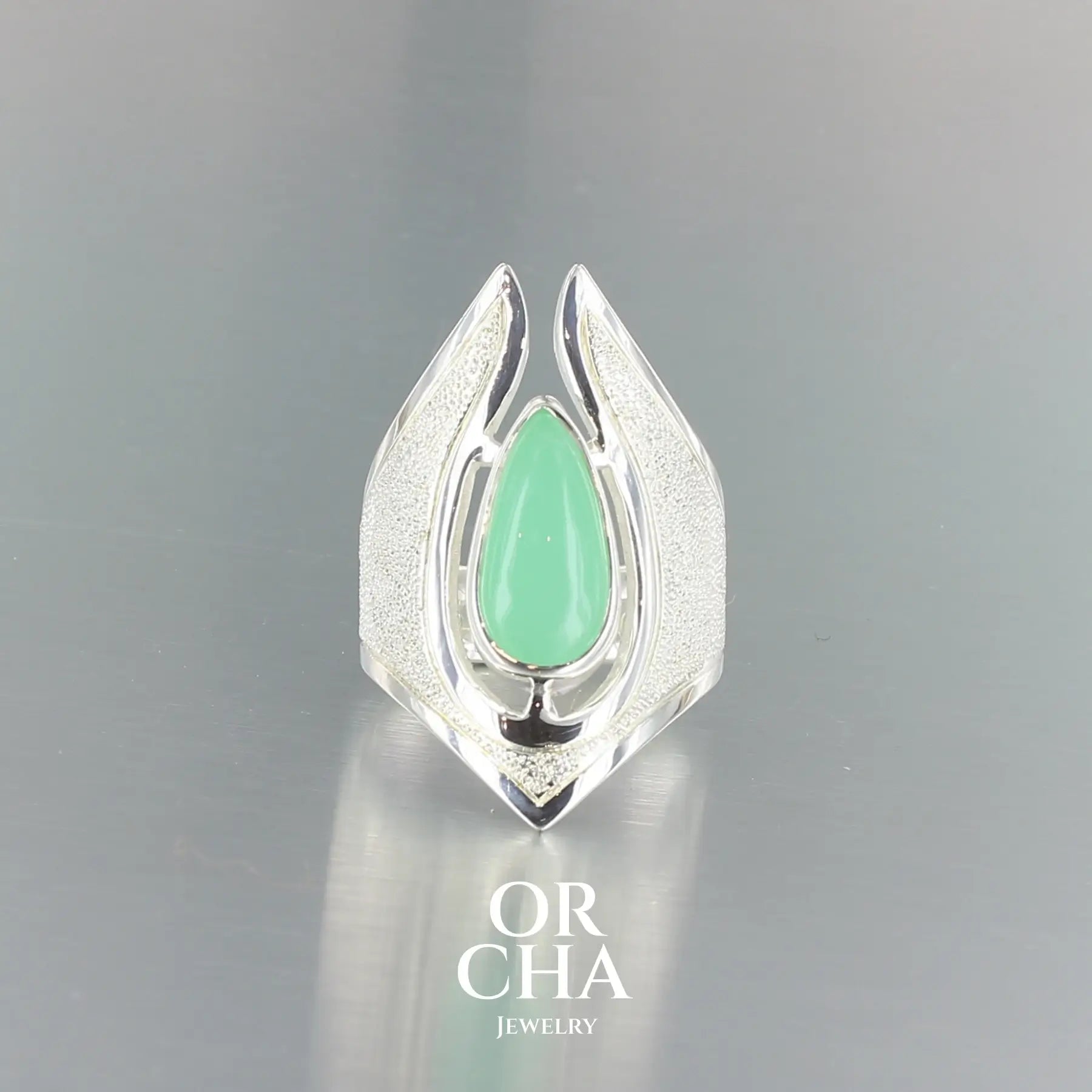 Bague de créateur pour femme en argent massif sertie d'une Chrysoprase. Pierre cabochon en forme de goutte de qualité opaque à translucide. Pierre naturelle de couleur vert  lumineux. bague réalisée en taille 55. Bijoux unique, éthique et durable présenté dans un coffret de notre marque, prêt à offrir. Livraison offerte, certificat d'authenticité, service client.