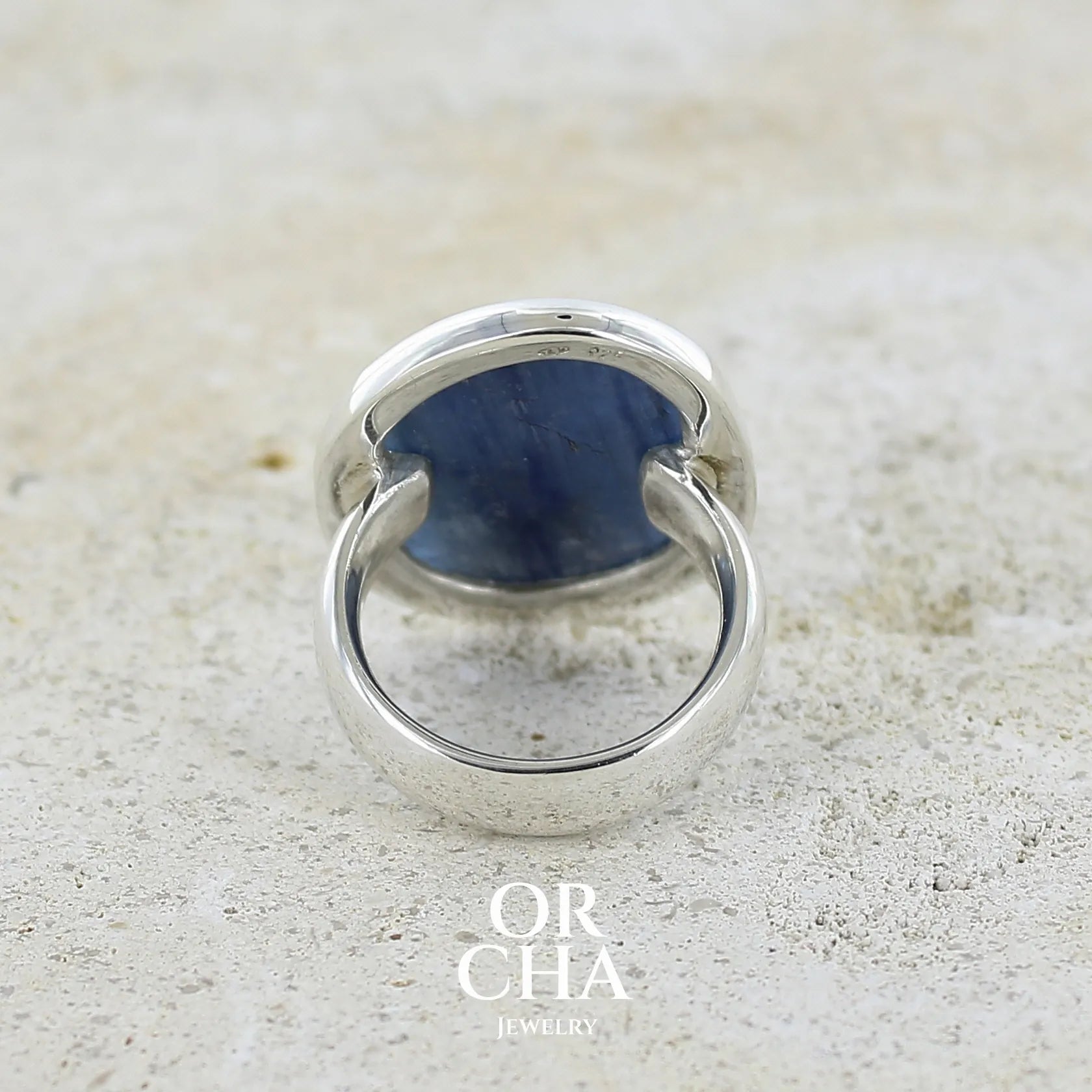Bague pour femme en argent massif sertie d'un cabochon de cyanite de couleur bleu jean nacré. Pierre translucide à inclusions. Bijou unique réalisée en taille 55 par Orcha Jewelry