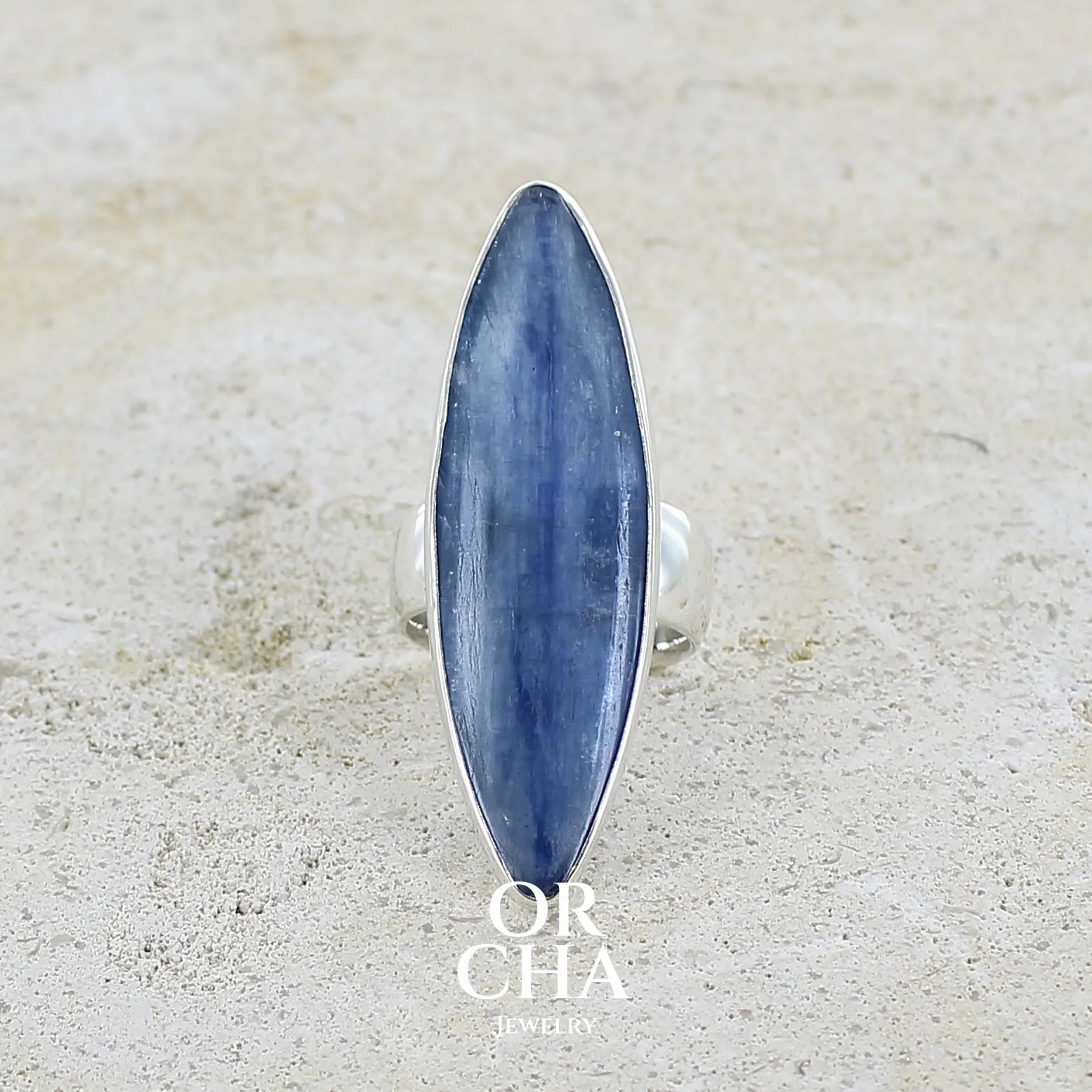 Bague marquise pour femme en argent massif sertie d'un cabochon de cyanite de couleur bleu jean nacré. Pierre translucide à inclusions. Bijou unique réalisée en taille 58 par Orchajewelry