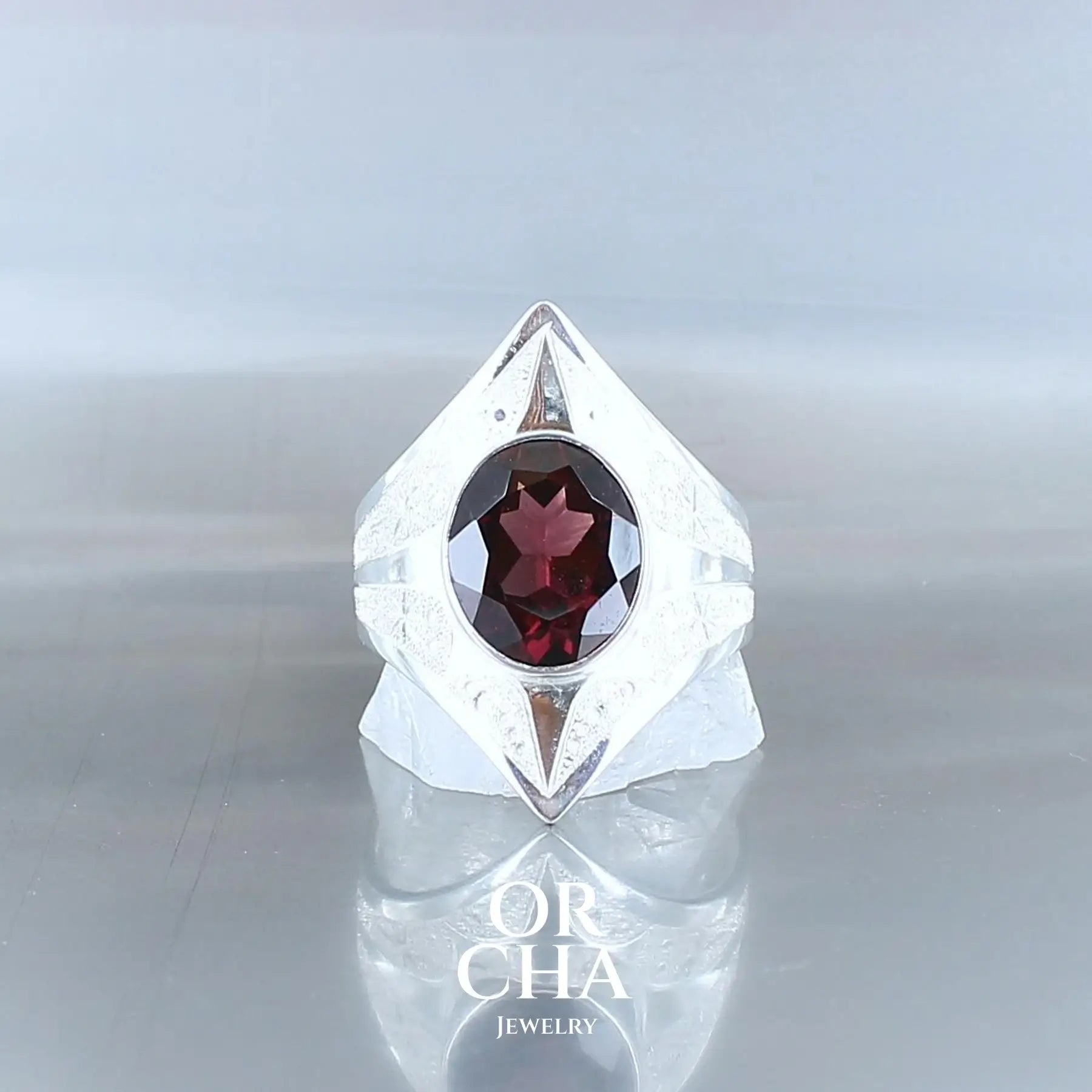 Bague pour femme en argent massif sculptée d'étoiles et sertie d'un Grenat Pyrope de couleur rouge foncé légèrement violacé. Pierre facettée transparente présentant des inclusions. Taille 61. Bijoux unique, éthique et durable présenté dans un coffret de notre marque, prêt à offrir. Livraison offerte, certificat d'authenticité, service client.