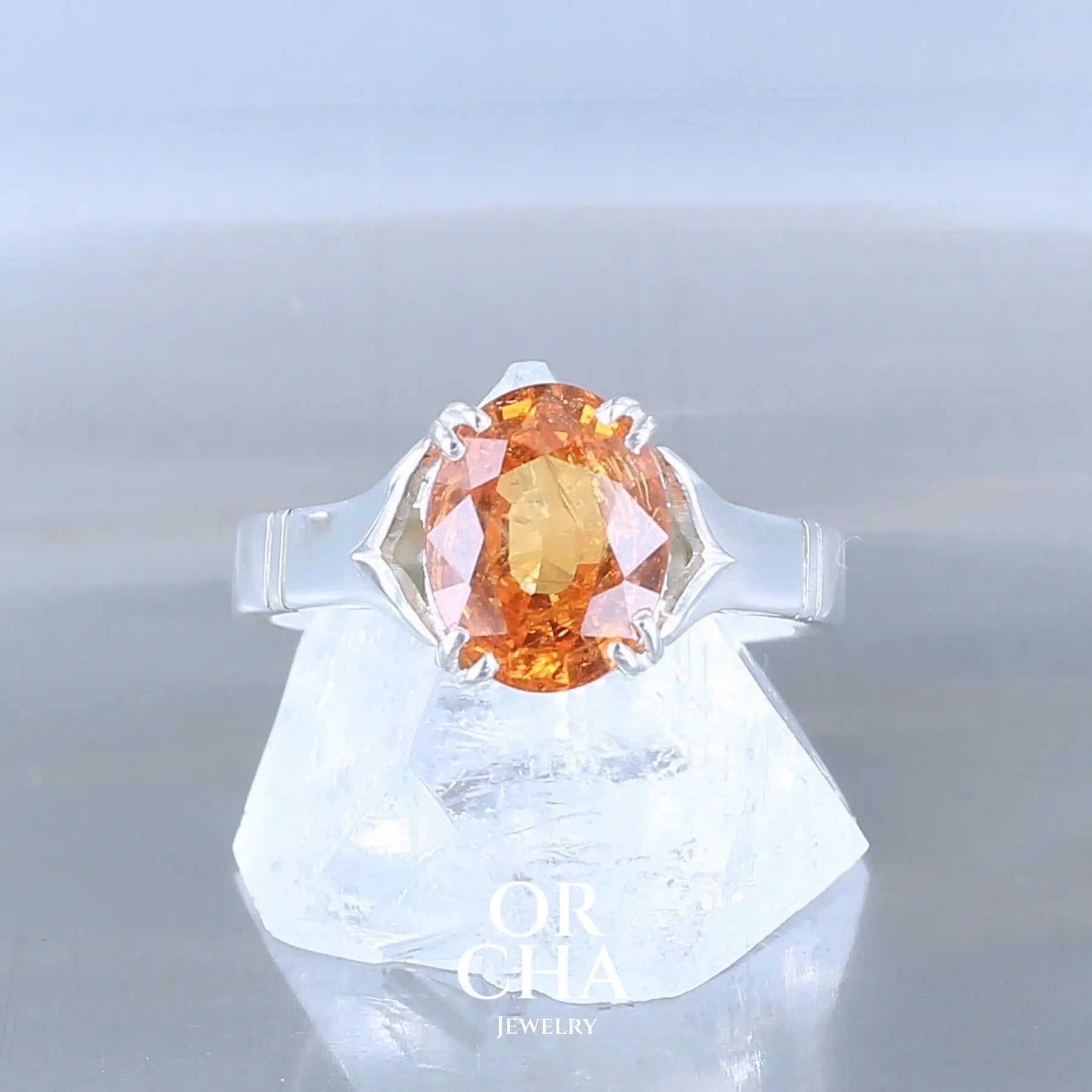 Bague solitaire pour femme en argent massif sertie d'un Grenat Spessartite à la couleur orange intense. Pierre facettée naturelle transparente présentant des inclusions. Taille 55. Bijoux unique, éthique et durable présenté dans un coffret de notre marque, prêt à offrir. Livraison offerte, certificat d'authenticité, service client.