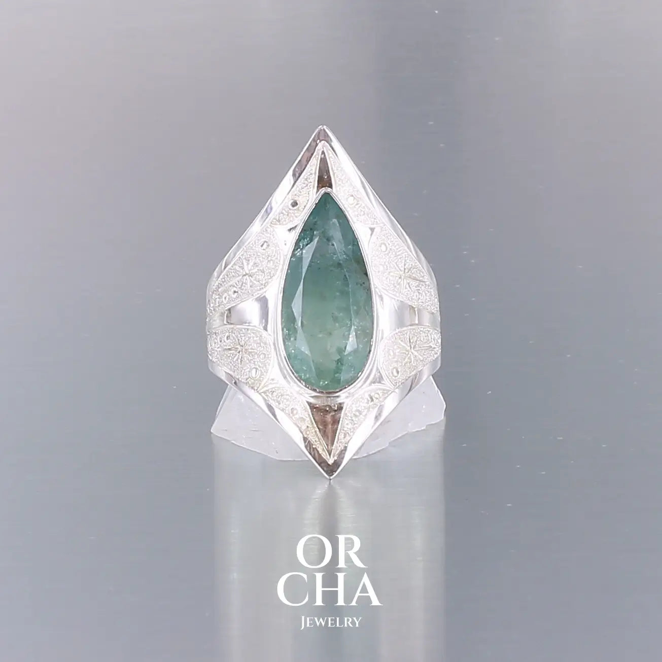 Bague pour femme en argent massif sculptées d'étoiles et autres corps célestes sertie d'une Aigue marine. Pierre facettée en forme de goutte, pierre naturelle aux nuances de bleus . Qualité  transparente avec inclusions, pierre naturelle n'ayant subit aucun traitement. Taille 60.5. Bijoux unique, éthique et durable présenté dans un coffret de notre marque, prêt à offrir. Livraison offerte, certificat d'authenticité, service client.
