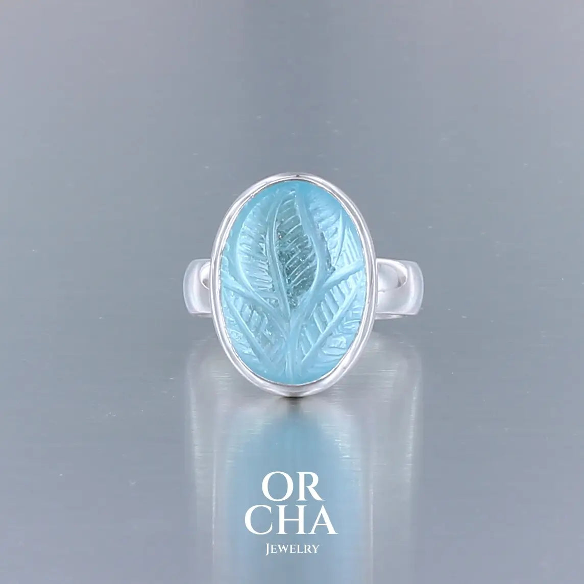Bague florale pour femme en argent massif sertie d'une topaze bleue sculptée de motifs végétaux. Cabochon de forme ovale, pierre de couleur bleu ciel intense. Qualité transparente. Taille 57. Bijoux unique, éthique et durable présenté dans un coffret de notre marque, prêt à offrir. Livraison offerte, certificat d'authenticité, service client