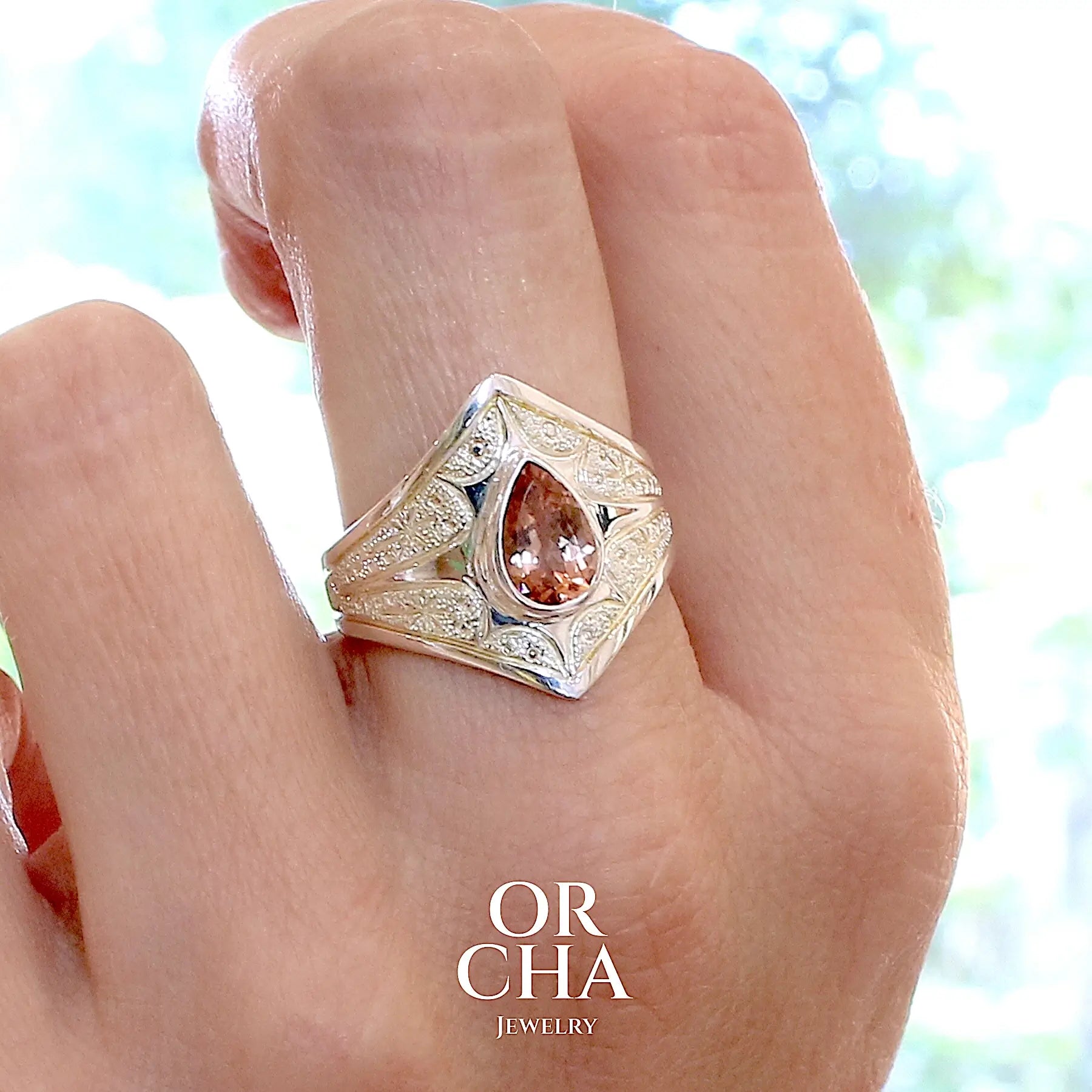 Bague sur modèle, pour femme, en argent massif sculptées d'étoiles et autres corps célestes sertie d'une Tourmaline rose ambré. Pierre facettée en forme de goutte, pierre naturelle de qualité transparente propre à l'oeil. Taille 59. Bijoux unique, éthique et durable présenté dans un coffret de notre marque, prêt à offrir. Livraison offerte, certificat d'authenticité, service client.
