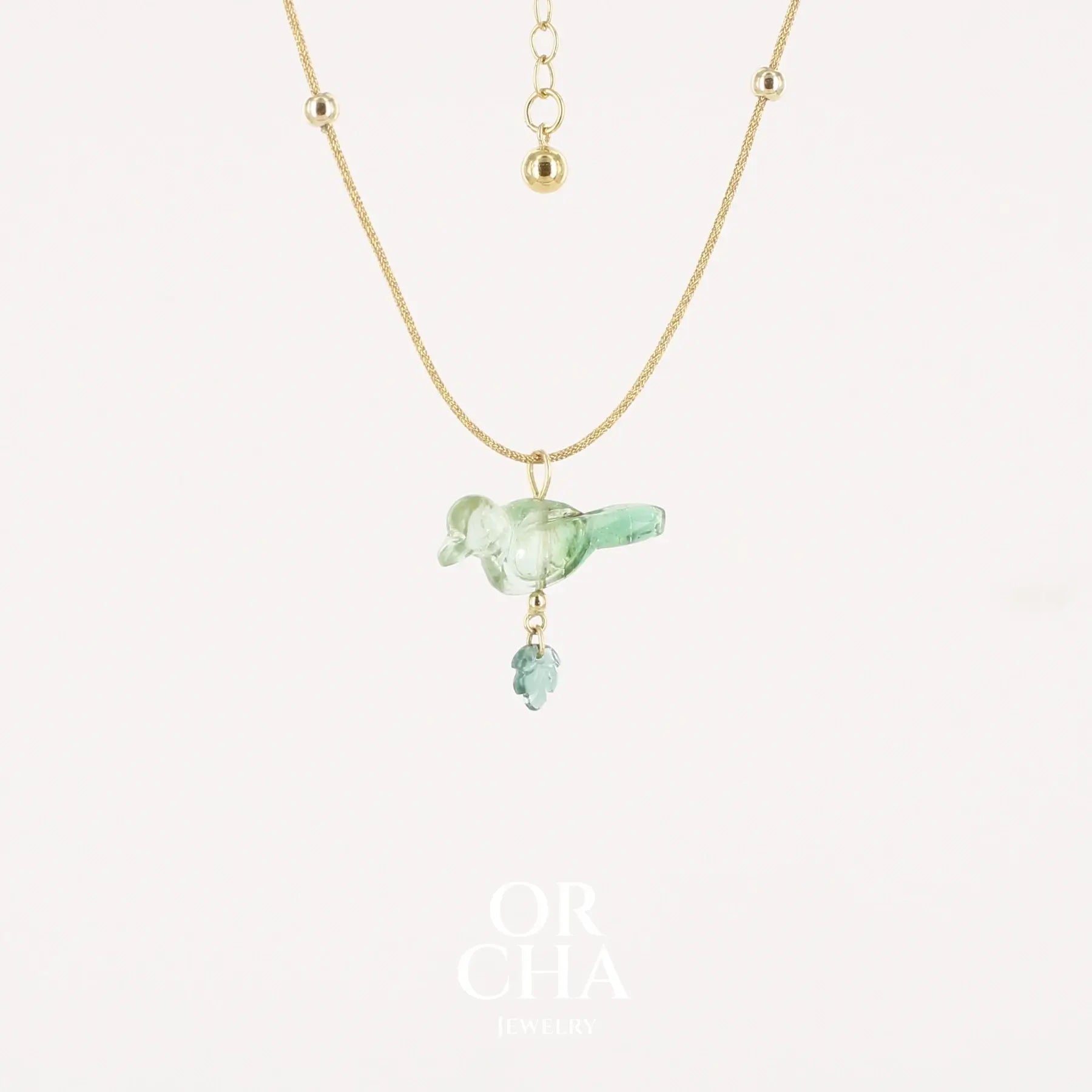 Collier Tourmaline verte bicolore sculptée à la main en 3 dimensions en forme d'oiseau plus une petite feuille, sertie en or 18k. Le pendentif est monté sur un collier corde doré scintillant, les apprêts utilisé sont en Gold filled ( or laminé ) Bijoux unique, éthique et durable présenté dans un coffret de notre marque, prêt à offrir. Livraison offerte, certificat d'authenticité, service client.
