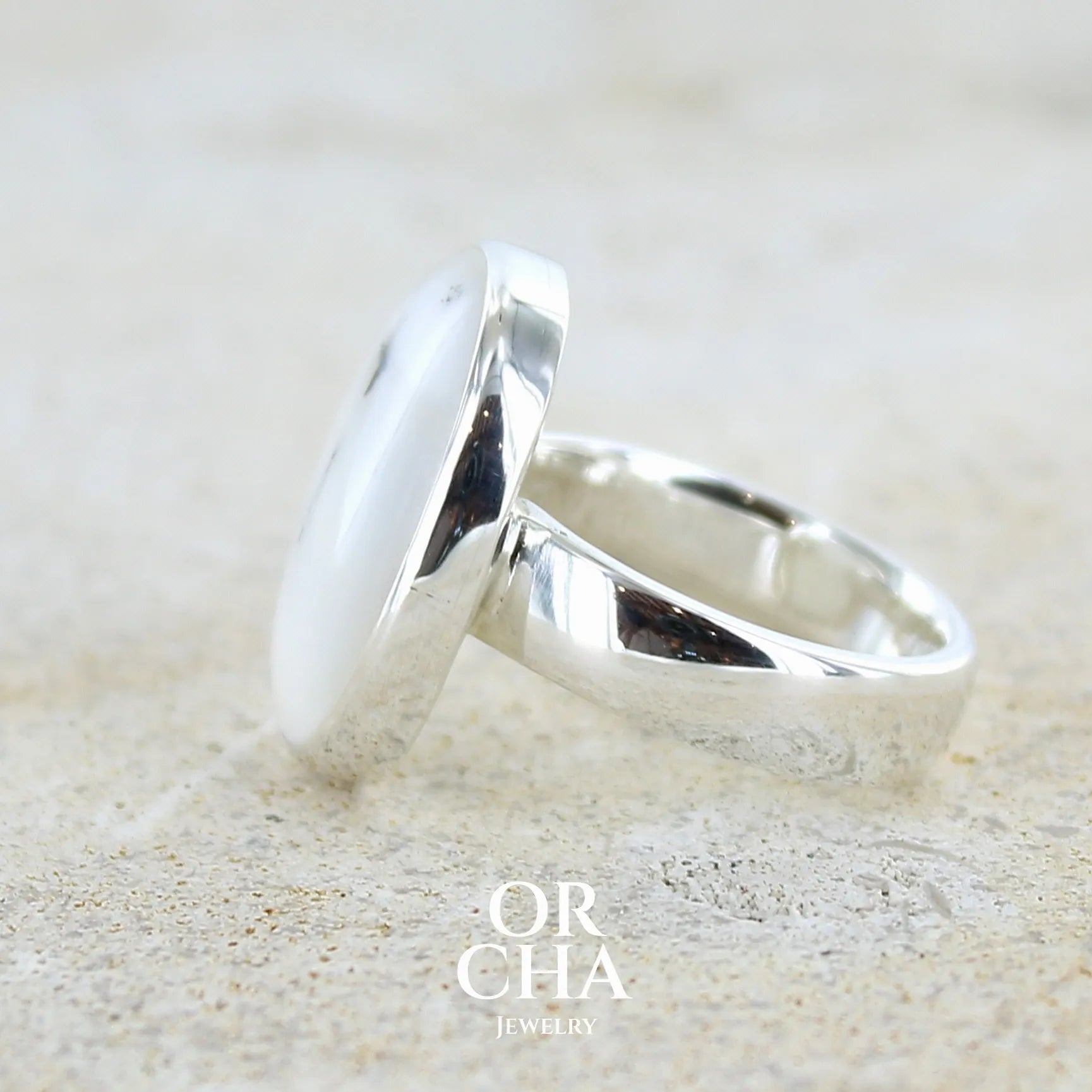 Détail d'une bague pour femme en argent massif sertie d'un cabochon ovale d'agate dendritique de couleur blanc pur et noir. Pierre opaque à inclusions paysages de dendrites de manganèse noires contrastées. Bijou unique réalisée en taille 54 par Orchajewelry