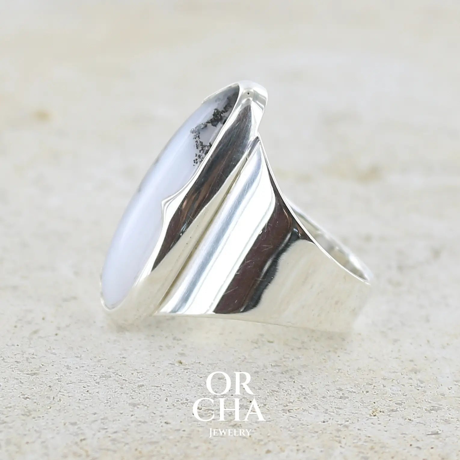 Détail d'une bague pour femme en argent massif sertie d'un cabochon d'agate dendritique de couleur blanc pur et noir. Pierre opaque translucide à inclusions arborescentes de dendrites de manganèse noires contrastées. Bijou unique réalisée en taille 58 par Orchajewelry
