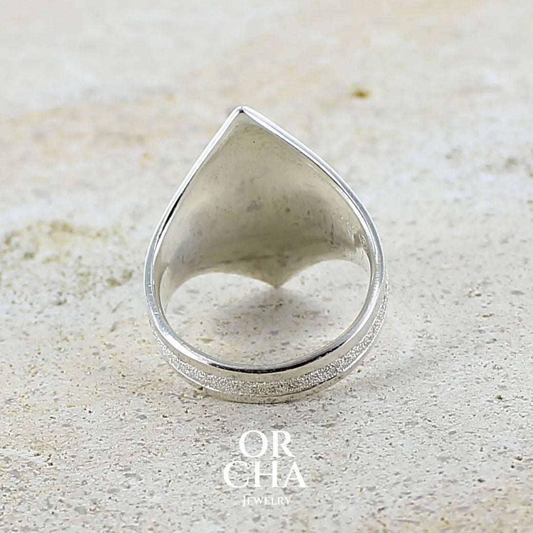vue de dos d'une bague pour femme en argent massif sculptées d'étoiles et autres corps célestes sertie d'un cabochon ovale de préhnite de couleur verte pastel lumineuse. Pierre naturelle de qualité transparente présentant des inclusions. Bijoux unique réalisé en taille 54,5 par Orchajewelry.