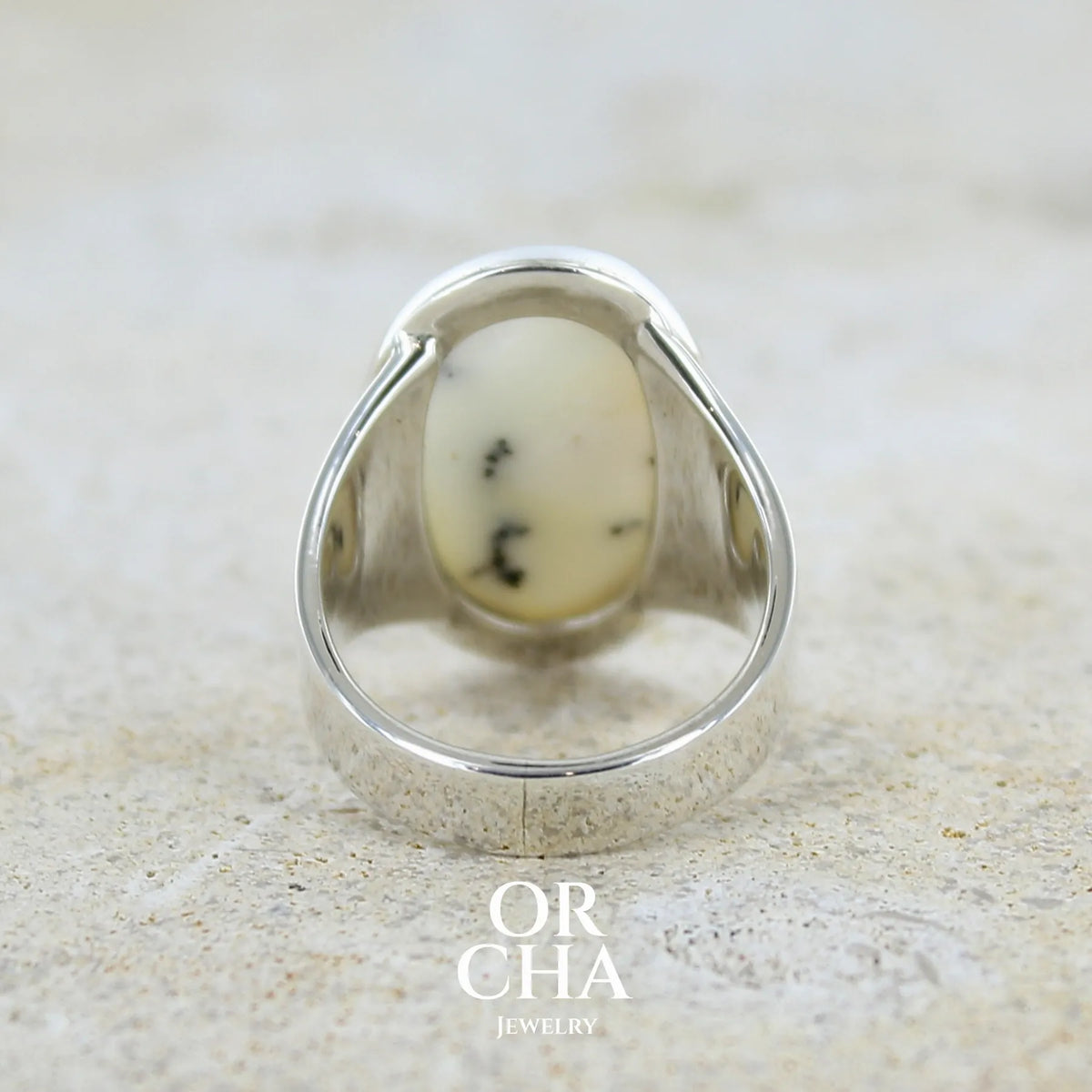 Vue de dos d'une bague pour femme en argent massif sertie d'un cabochon ovale d'agate dendritique de couleur blanc pur et noir. Pierre opaque translucide à inclusions paysages de dendrites de manganèse noires contrastées. Bijou unique réalisé en taille 54 par Orchajewelry