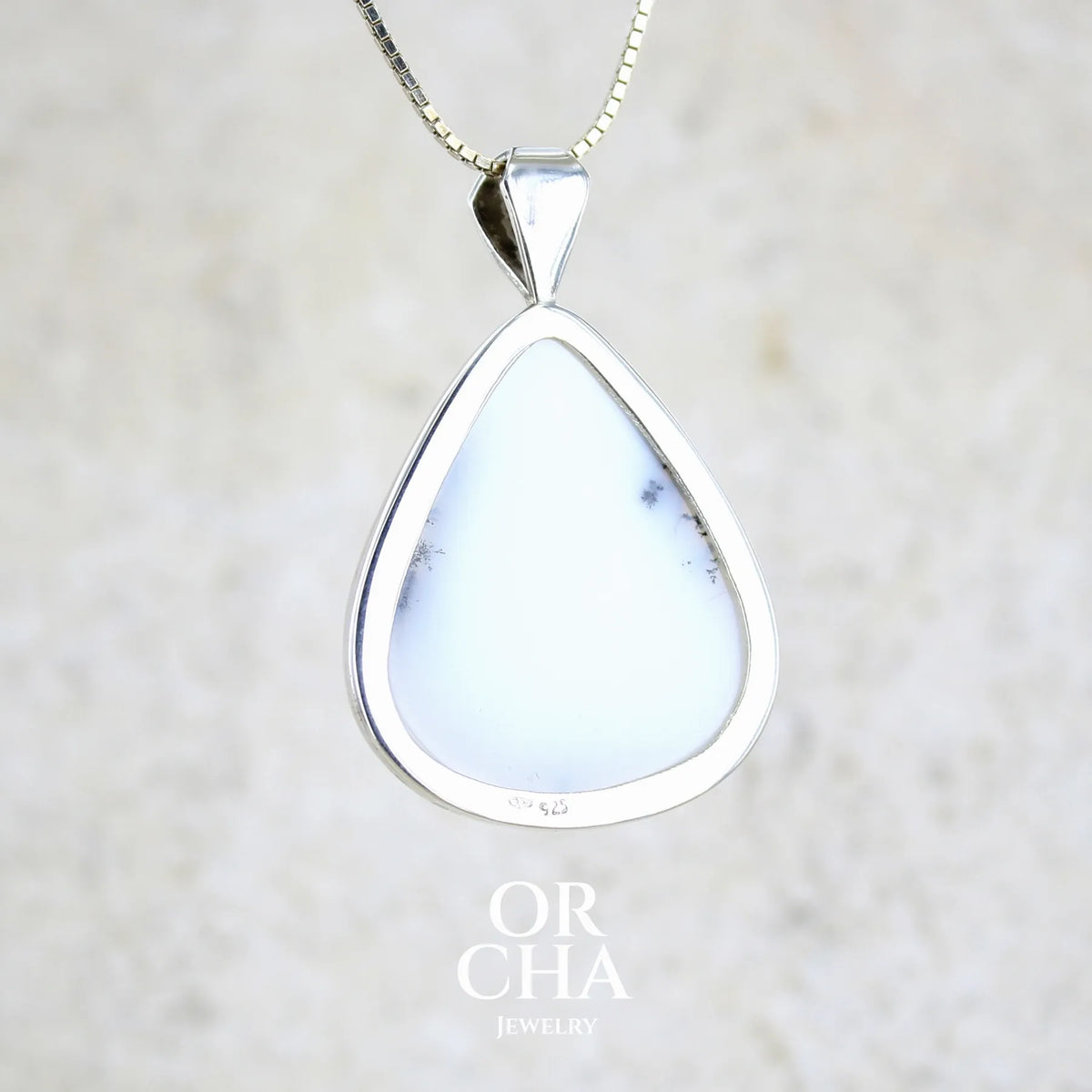Vue de dos d'un pendentif pour femme en argent massif sertie d'un cabochon en forme de goutte  d'agate dendritique de couleur blanc pur et noir. Pierre opaque à translucide à inclusions paysages de dendrites de manganèse noires contrastées. Bijou unique réalisé par Orchajewelry