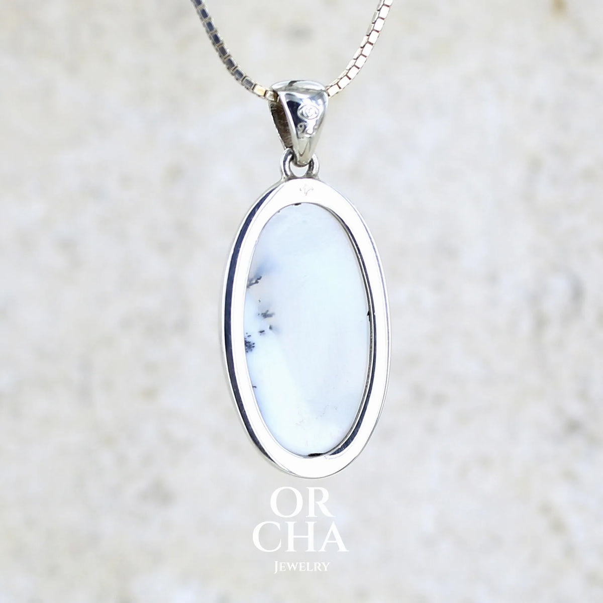 Vue de dos d'un pendentif pour femme en argent massif sertie d'un cabochon de forme ovale d'agate dendritique de couleur blanc pur et noir. Pierre opaque à translucide à inclusions paysages de dendrites de manganèse noires contrastées. Bijou unique réalisé par Orchajewelry