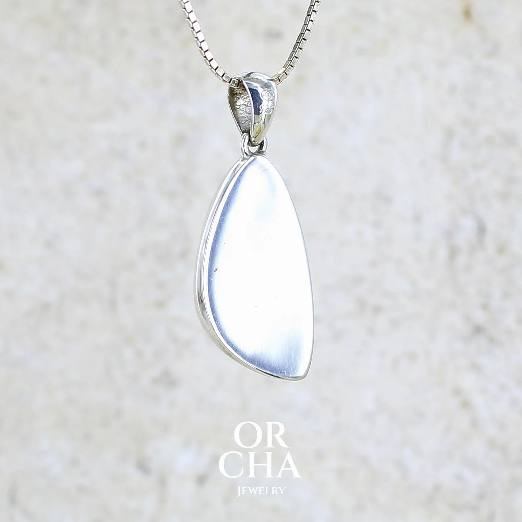 Vue de dos d'un pendentif pour femme en argent massif sertie d'un cabochon en forme d'aile d'agate dendritique de couleur blanc pur et noir. Pierre opaque à translucide à inclusions paysages de dendrites de manganèse noires contrastées. Bijou unique réalisé par Orchajewelry