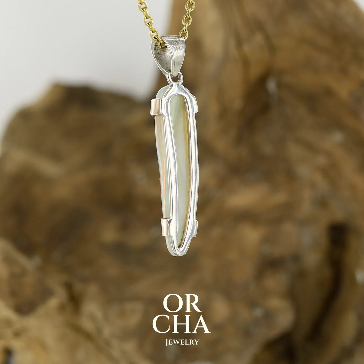 Vue de dos d'un pendentif pour femme en or jaune massif 18k serti d'une opale cristal aux feux étoilés multicolores à dominantes vert et jaune. Cabochon de 1 carat taille en forme de goutte de qualité transparente. Opale australienne de Mintabie. Bijou unique réalisé par Orchajewelry