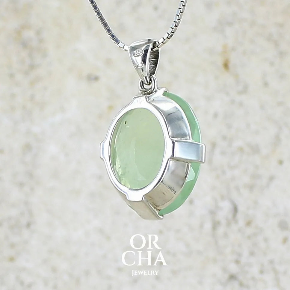 Vue de dos d'un pendentif ovale en argent massif, serti d'un cabochon facetté de préhnite de couleur verte jaune pastel. Pierre de qualité translucide comportant des inclusions. Bijoux unique par Orcha Jewelry