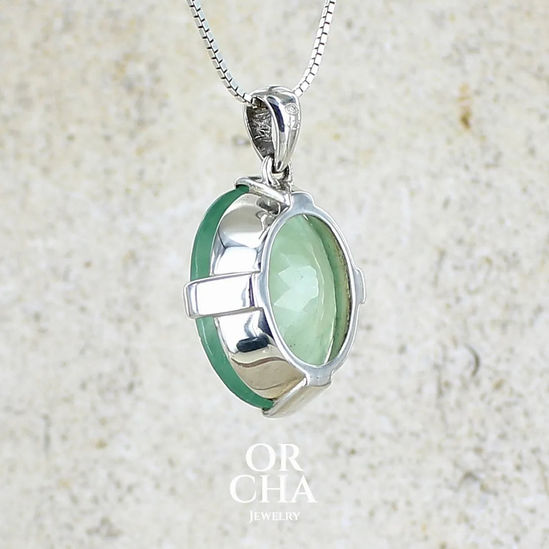 Vur de dos d'un pendentif ovale en argent massif, serti d'un cabochon facetté de préhnite de couleur verte pastel. Pierre de qualité translucide comportant des inclusions. Bijoux unique par Orcha Jewelry