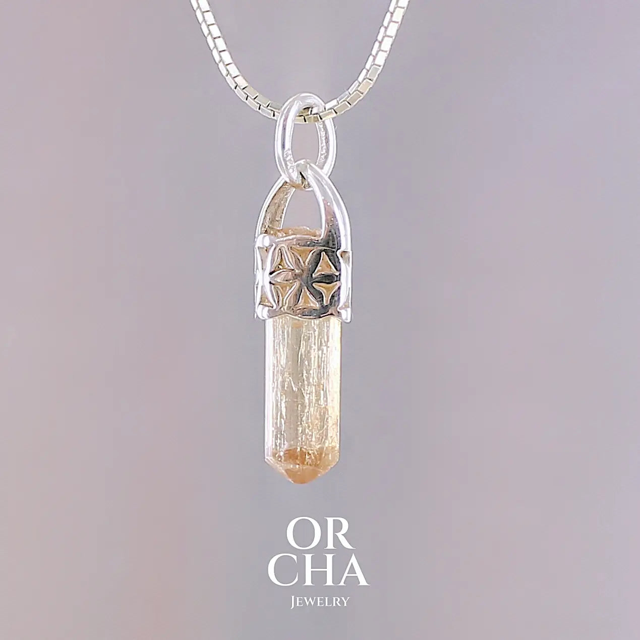 Pendentif cristal de topaze impériale en argent massif, sertissage filigrané de fleurs de vie. La pierre est  de couleur jaune arrangé pêche. Cristal brute, transparent, inclusions naturelles. Bijoux unique, éthique et durable présenté dans un coffret de notre marque, prêt à offrir. Livraison offerte, certificat d'authenticité, service client.