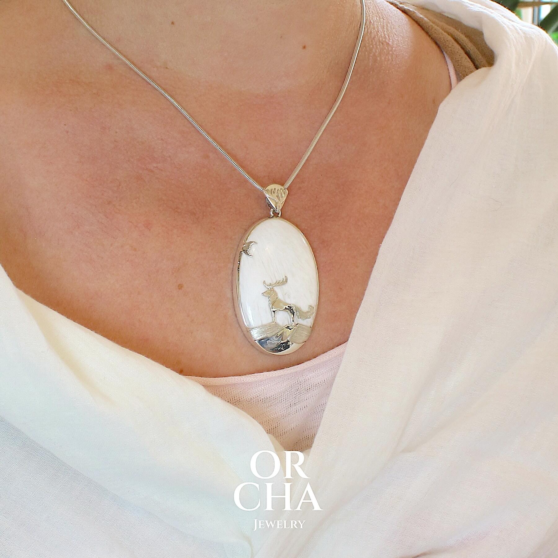 Pendentif de créateur en argent massif, où s'illustre un animal fantastique de type cerf loup sculpté en argent massif et serti sur un cabochon de scolécite. Pierre blanche opaque naturelle aux reflets soyeux. Bijoux unique, éthique et durable présenté dans un coffret de notre marque, prêt à offrir. Livraison offerte, certificat d'authenticité, service client.