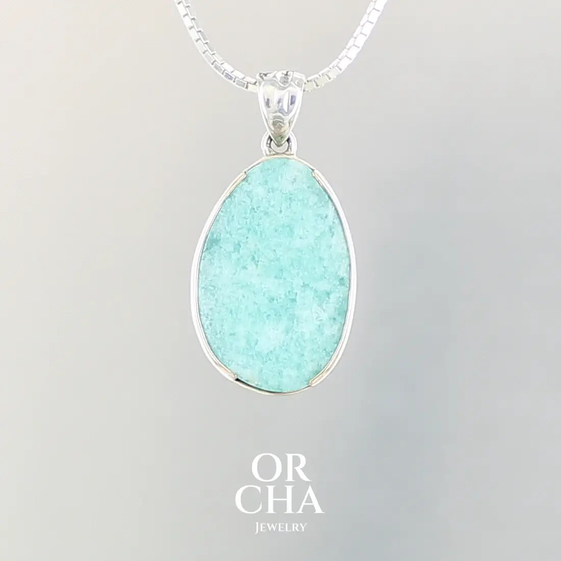 Pendentif pour femme en argent massif et or 12K, serti d'une Amazonite de couleur bleu verte clair. Pierre cabochon de forme ovale translucide présentant des inclusions. Bijoux unique, éthique et durable présenté dans un coffret de notre marque, prêt à offrir. Livraison offerte, certificat d'authenticité, service client