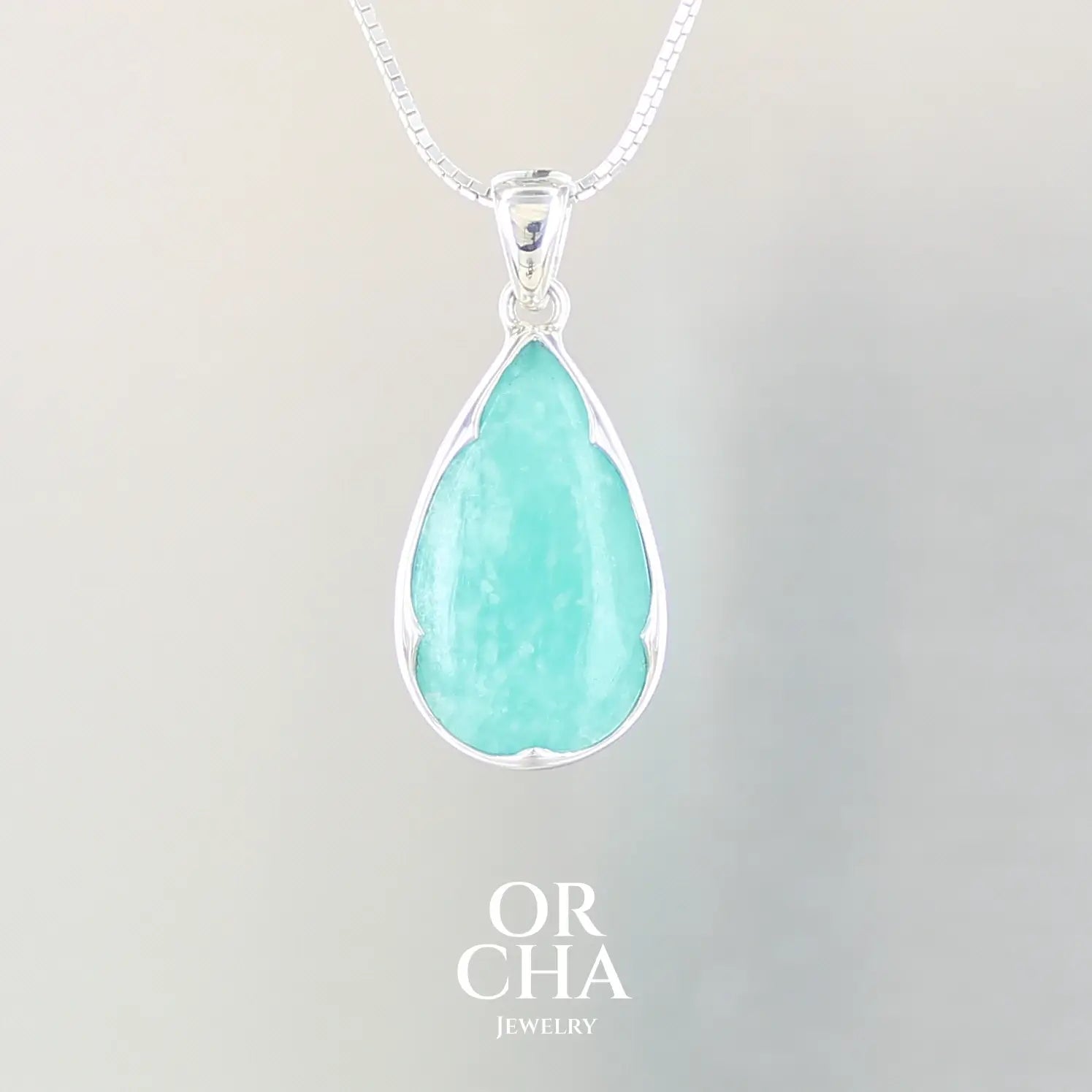 Pendentif pour femme en argent massif serti d'une Amazonite de couleur bleu intense. Pierre cabochon en forme de goutte translucide présentant des inclusions. Bijoux unique, éthique et durable présenté dans un coffret de notre marque, prêt à offrir. Livraison offerte, certificat d'authenticité, service client