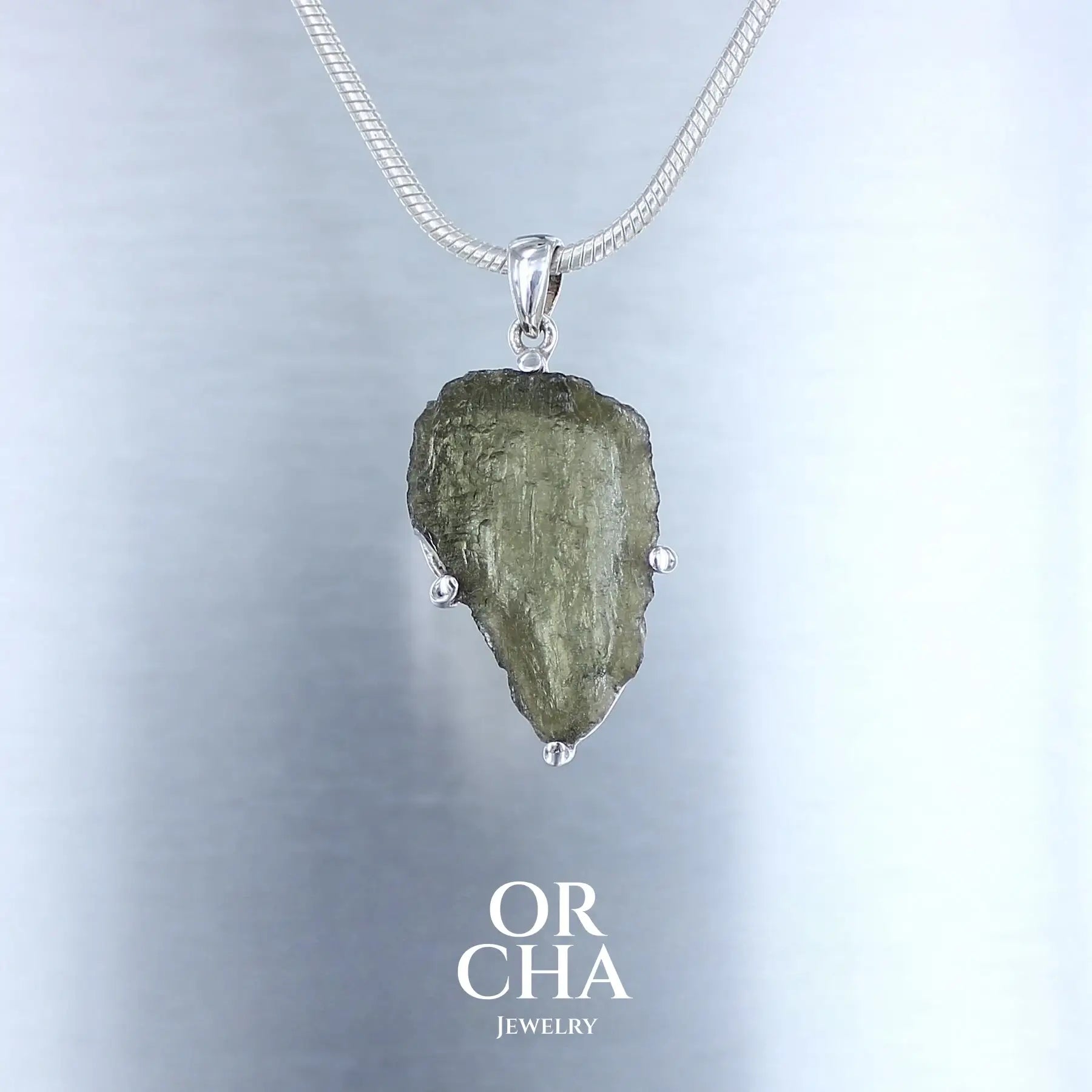 pendentif pour homme en argent massif serti d'une Moldavite brute. Pierre  brute naturelle transparente de couleur verte. Bijoux unique, éthique et durable présenté dans un coffret de notre marque, prêt à offrir. Livraison offerte, certificat d'authenticité, service client.