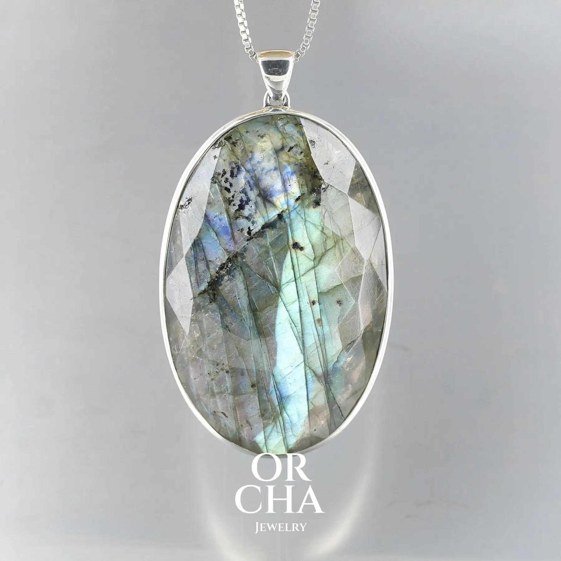 Grand pendentif pour femme en argent massif serti d'une labradorite aux reflets bleus verts selon la lumière. Pierre facettée naturelle translucide présentant des inclusions fréquents sur ce type de pierre. Bijoux unique, éthique et durable présenté dans un coffret de notre marque, prêt à offrir. Livraison offerte, certificat d'authenticité, service client.
