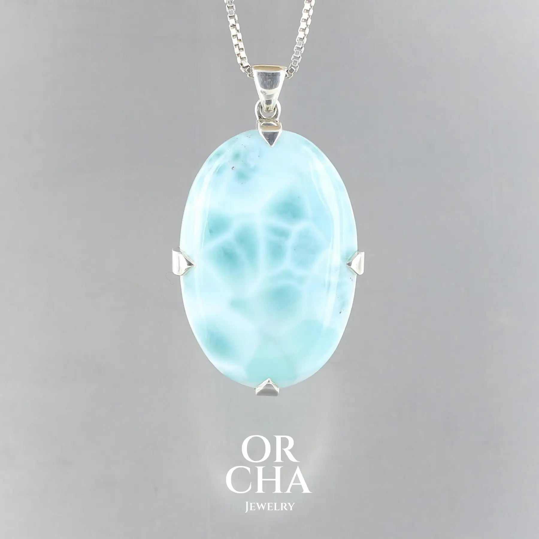 Grand pendentif pour femme en argent massif serti d'un cabochon ovale de Larimar de couleur bleu lagon. Pierre naturelle de qualité opaque. Bijoux unique, éthique et durable présenté dans un coffret de notre marque, prêt à offrir. Livraison offerte, certificat d'authenticité, service client