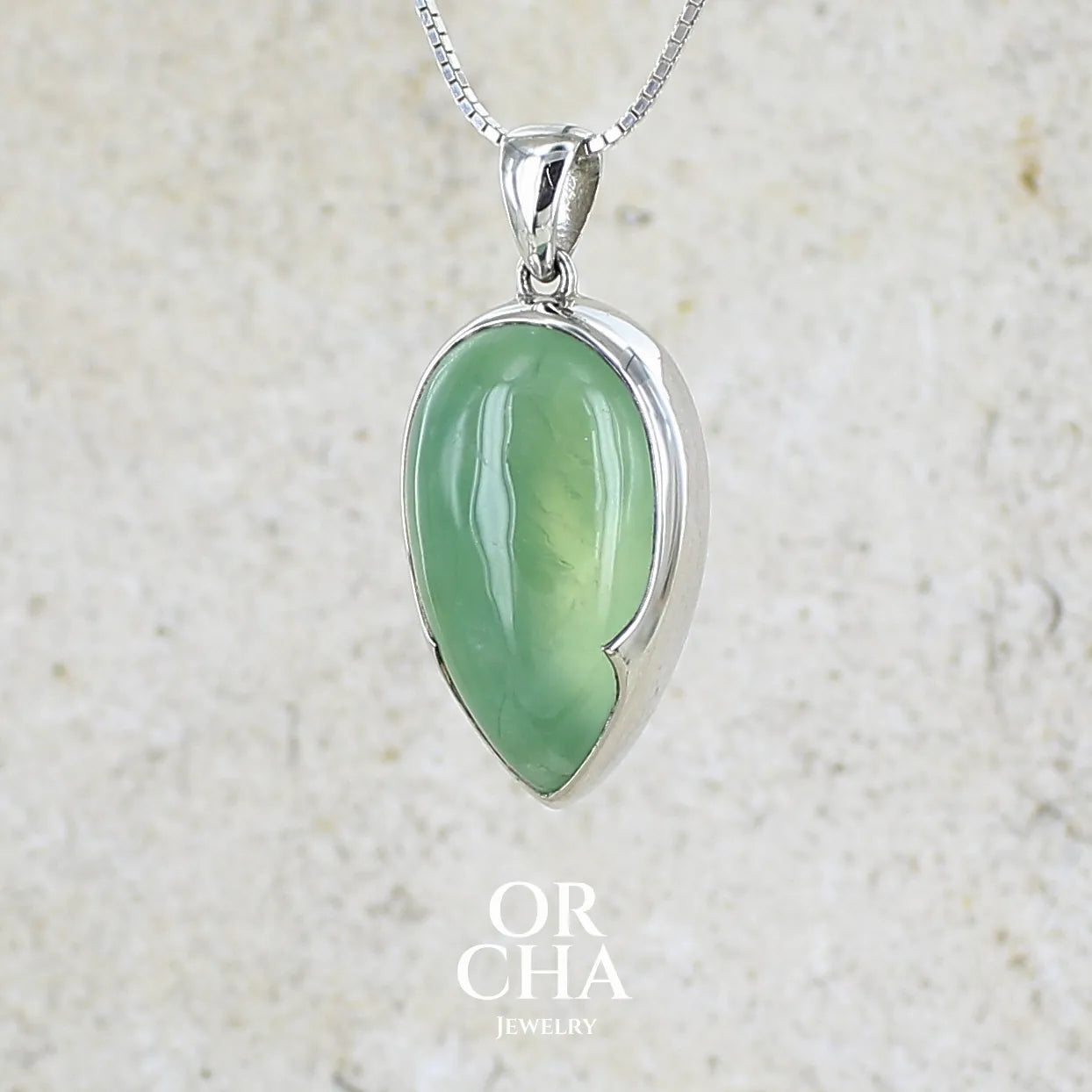 Pendentif pour femme en argent massif serti d'une préhnite de couleur vert jaune clair. Pierre naturelle taillée en cabochon en forme de goutte. Bijoux unique par orchajewelry.