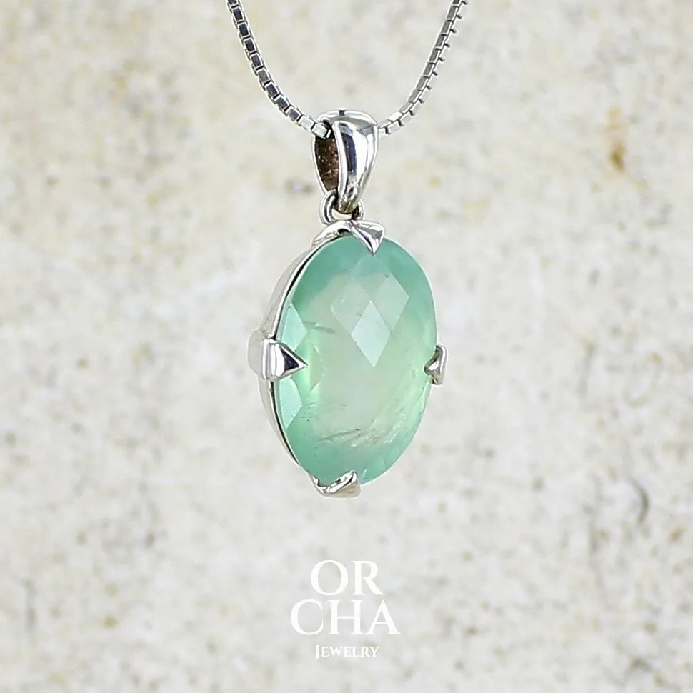 Pendentif ovale en argent massif, serti d'un cabochon facetté de préhnite de couleur bleue verte. Pierre de qualité translucide comportant des inclusions. blanches. Bijoux unique par Orcha Jewelry