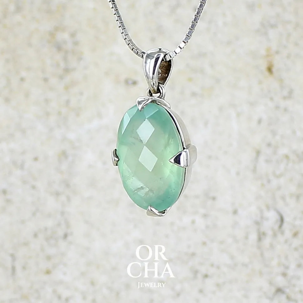 Pendentif ovale en argent massif, serti d'un cabochon facetté de préhnite de couleur bleue verte. Pierre de qualité translucide comportant des inclusions. blanches. Bijoux unique par Orcha Jewelry