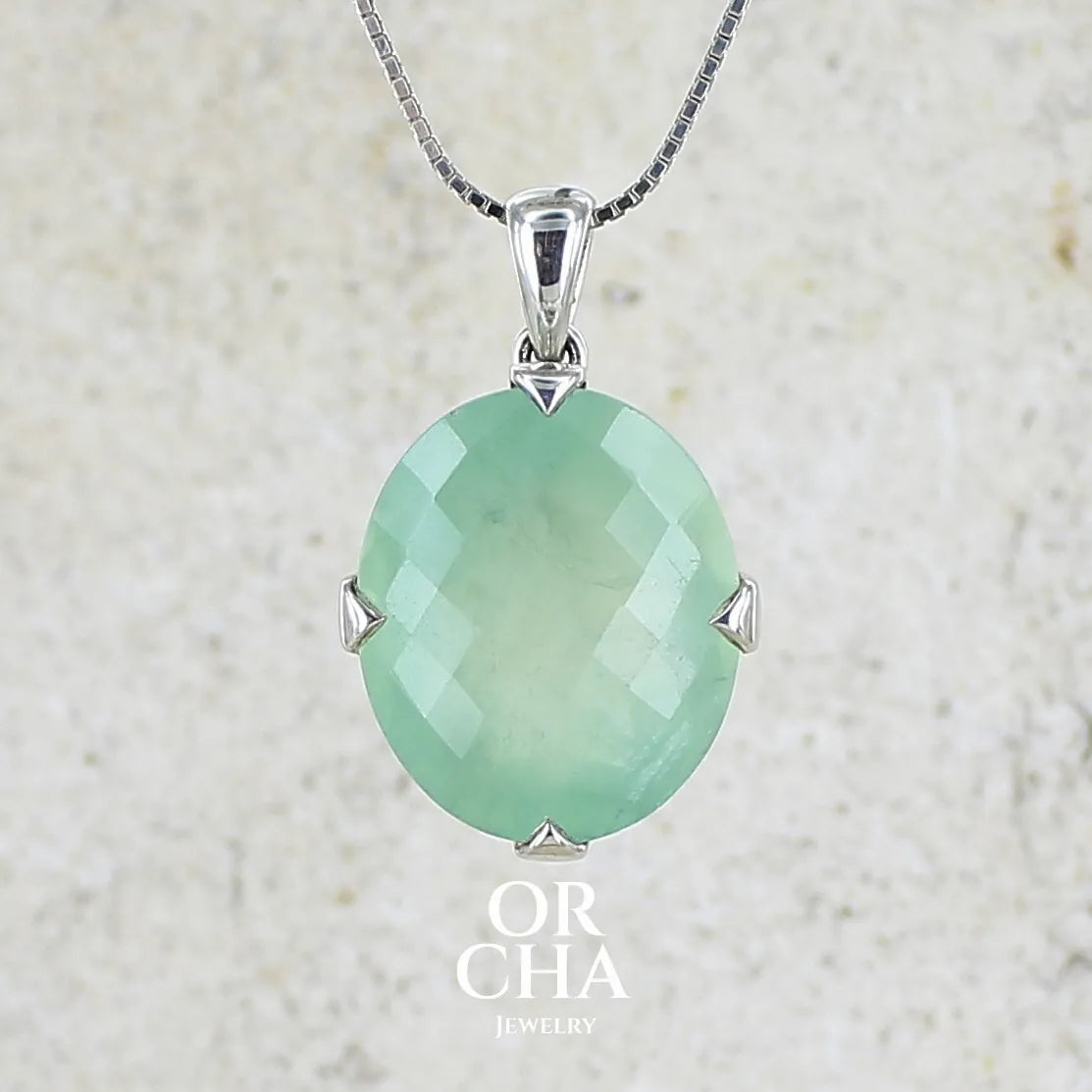 Pendentif ovale en argent massif, serti d'un cabochon facetté de préhnite de couleur verte pastel. Pierre de qualité translucide comportant des inclusions. Bijoux unique par Orcha Jewelry