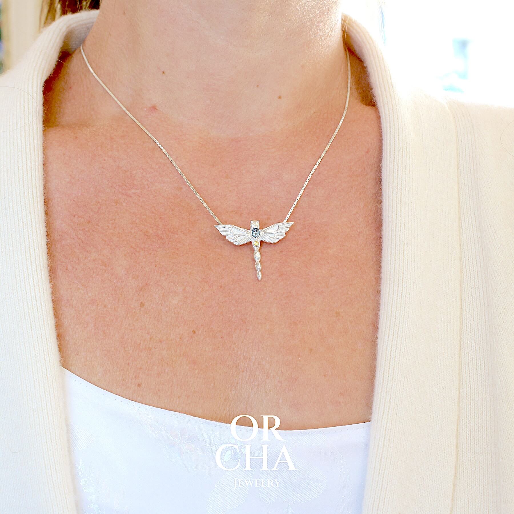 Pendentif libellule en argent massif serti d'une aigue-marine et saphir jaune. Pierre de qualité transparente propre à l'oeil. Bijoux unique, éthique et durable présenté dans un coffret de notre marque, prêt à offrir. Livraison offerte, certificat d'authenticité, service client.
