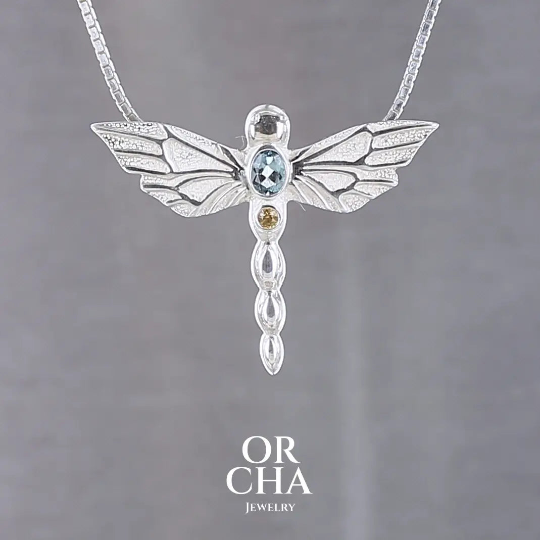 Pendentif libellule en argent massif serti d'une aigue-marine et saphir jaune. Pierre de qualité transparente propre à l'oeil. Bijoux unique, éthique et durable présenté dans un coffret de notre marque, prêt à offrir. Livraison offerte, certificat d'authenticité, service client.
