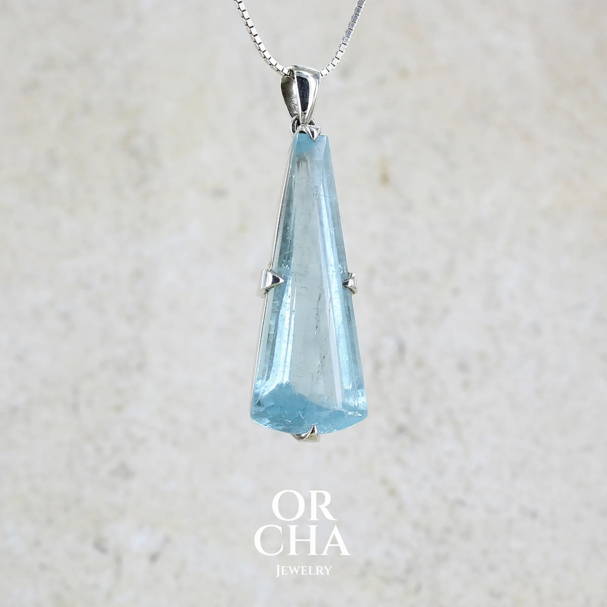 Pendentif en argent massif sertie d'une aigue marine taillée de 32 carats de couleur bleu clair profond et lumineux, pierre transparente avec inclusions. Pierre naturelle facettée de forme triangulaire allongé. Bijoux unique réalisée par Orchajewelry