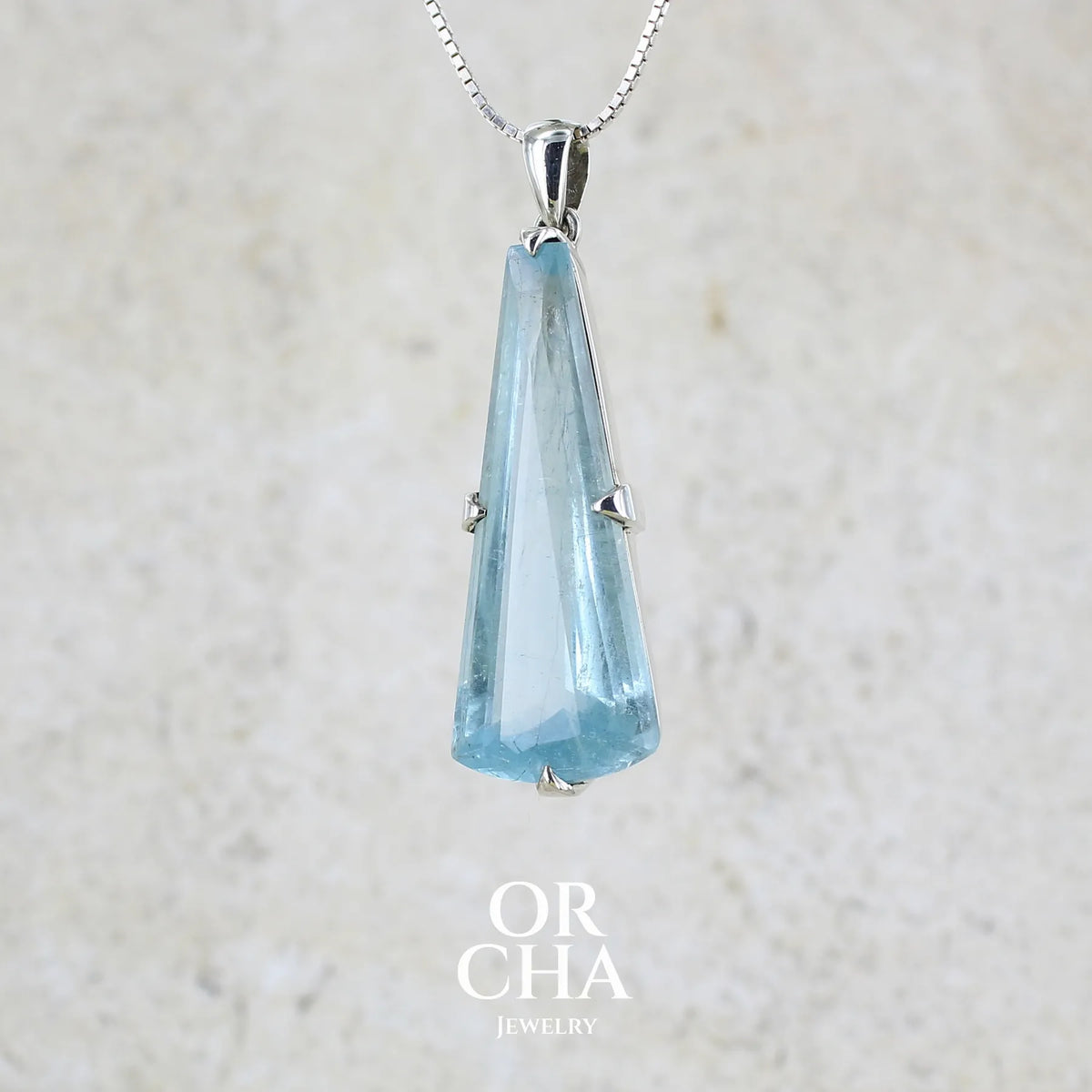 Pendentif en argent massif sertie d'une aigue marine taillée de 32 carats de couleur bleu clair profond et lumineux, pierre transparente avec inclusions. Pierre naturelle facettée de forme triangulaire allongé. Bijoux unique réalisée par Orchajewelry